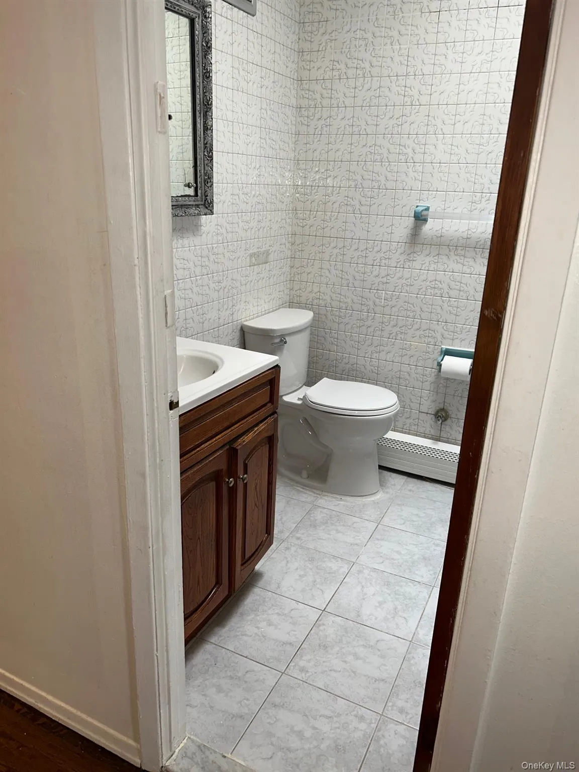 Half bath with tile walls, vanity, and baseboard heating Half bath with tile walls, vanity, and baseboard heating