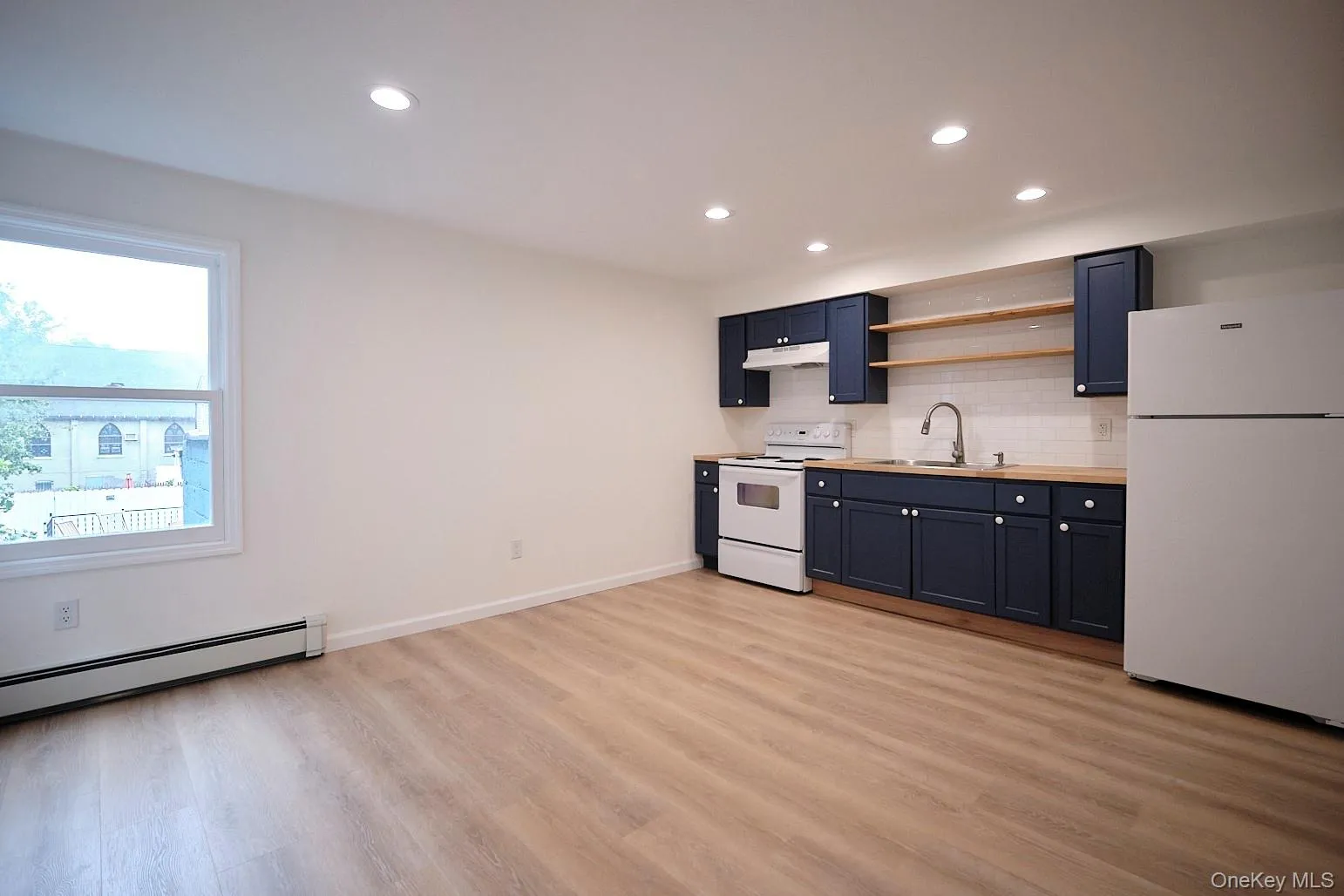 Kitchen featuring white appliances, light countertops, open shelves, backsplash, and recessed lighting Kitchen featuring white appliances, light countertops, open shelves, backsplash, and recessed lighting