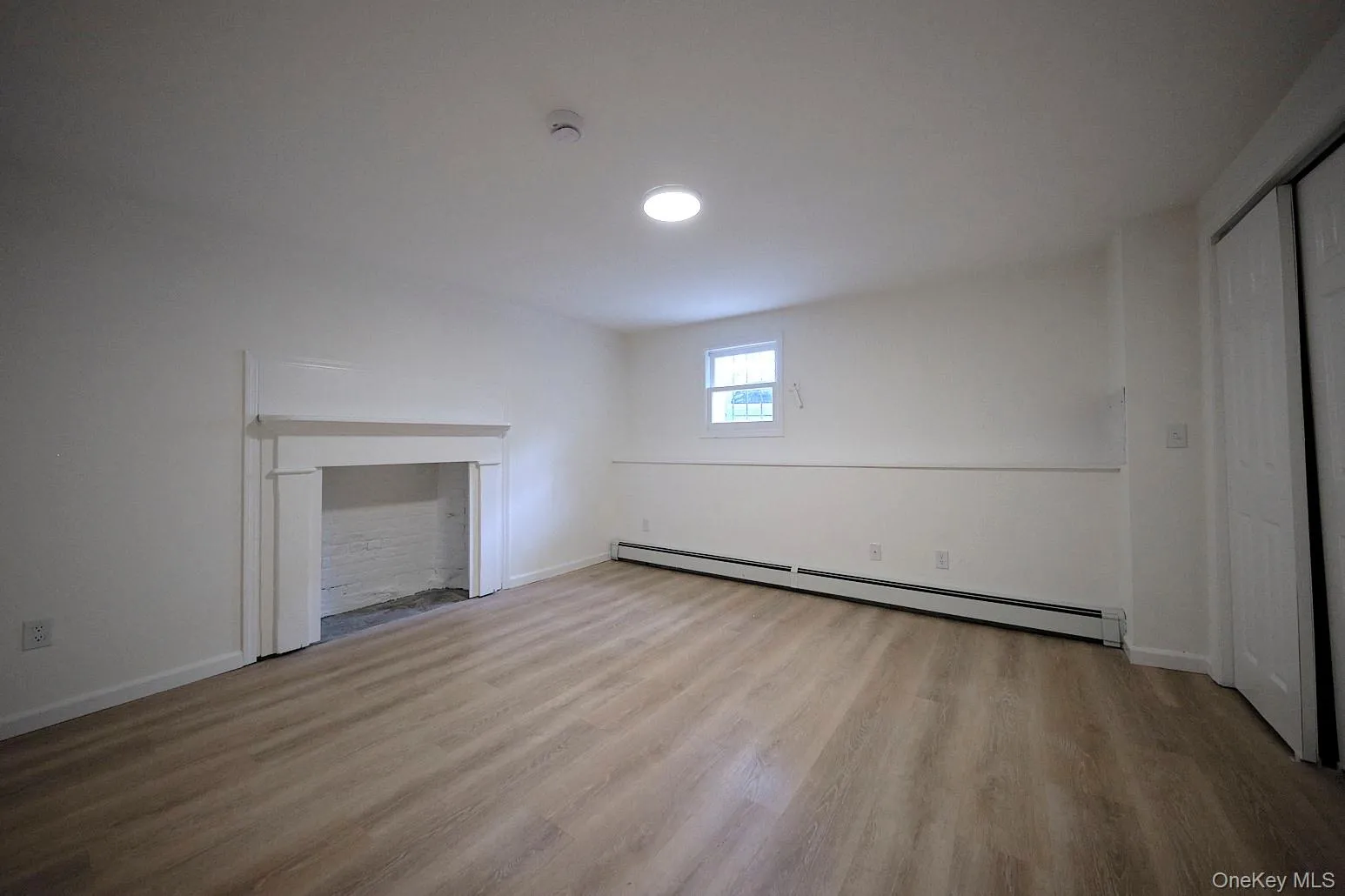 Unfurnished living room with a baseboard heating unit and light wood-type flooring Unfurnished living room with a baseboard heating unit and light wood-type flooring