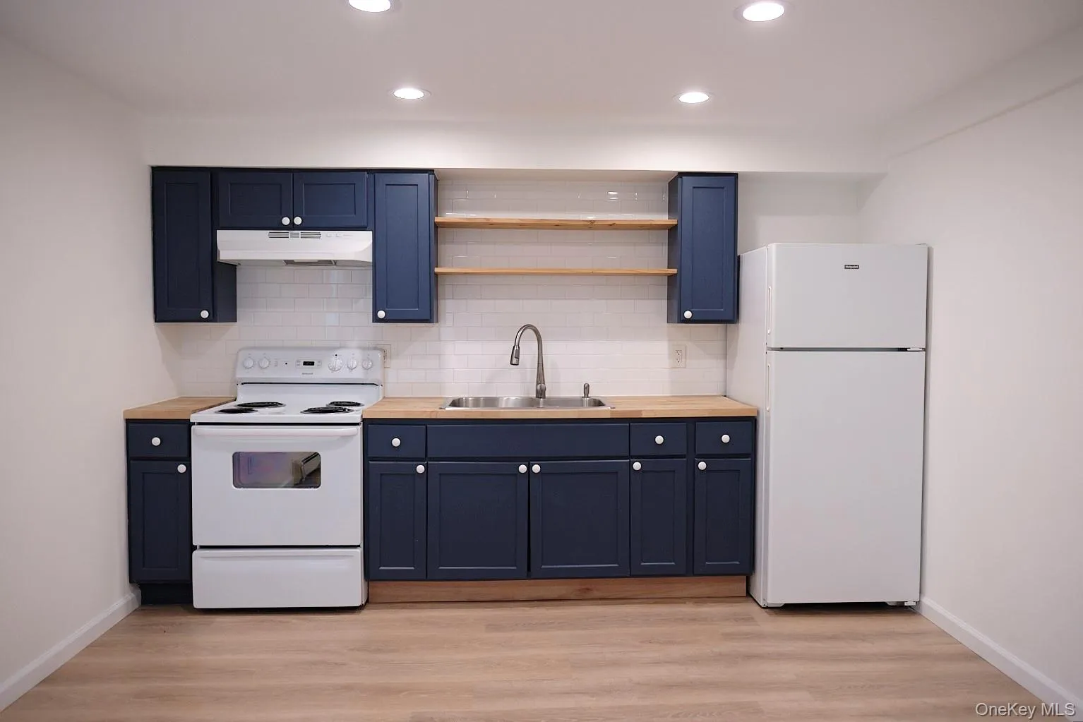 Kitchen featuring white appliances, open shelves, backsplash, recessed lighting, and light wood finished floors Kitchen featuring white appliances, open shelves, backsplash, recessed lighting, and light wood finished floors