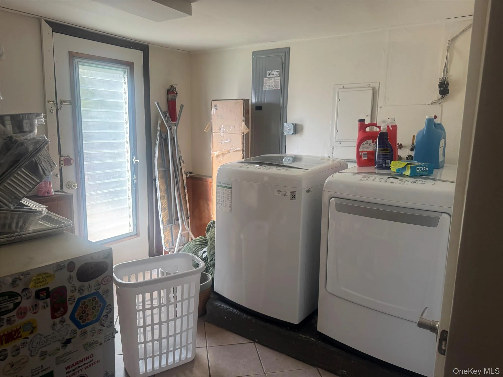 Washroom featuring electric panel, light tile patterned flooring, and washing machine and dryer Washroom featuring electric panel, light tile patterned flooring, and washing machine and dryer