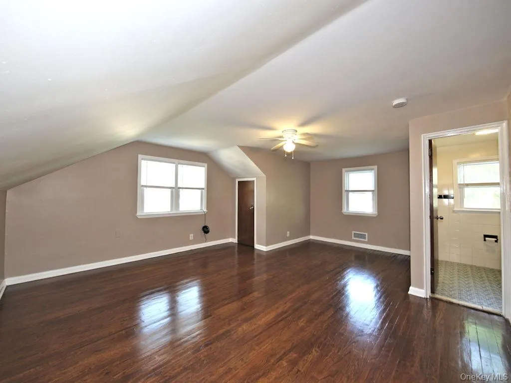 Additional living space featuring dark wood-style flooring, vaulted ceiling, and a ceiling fan Additional living space featuring dark wood-style flooring, vaulted ceiling, and a ceiling fan