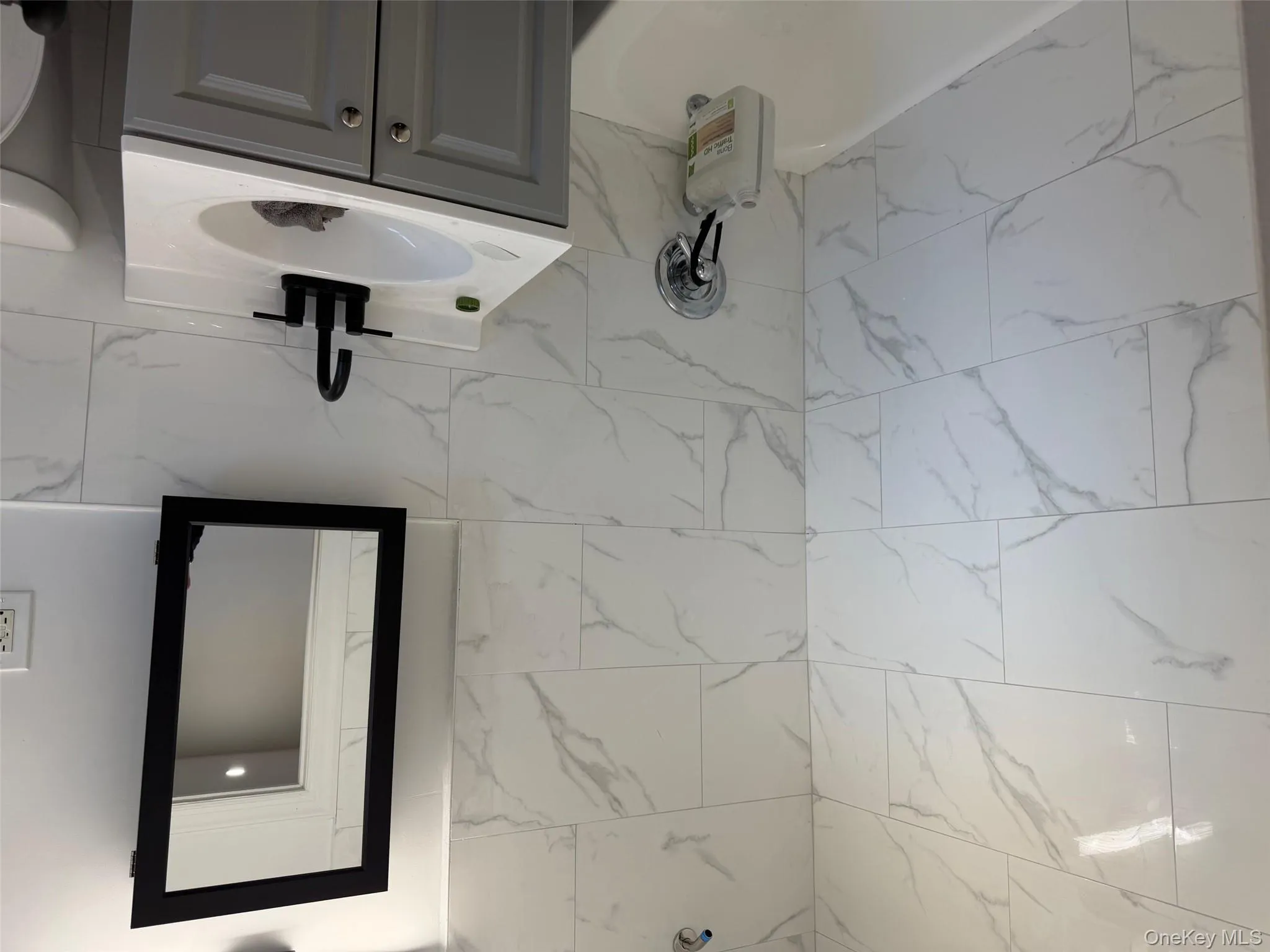 Full bathroom featuring shower / bath combination, vanity, and tile walls Full bathroom featuring shower / bath combination, vanity, and tile walls