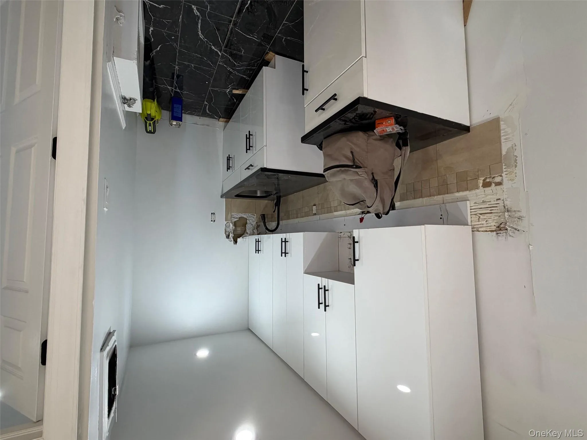 Kitchen featuring white cabinetry, tasteful backsplash, dark marble finish flooring, and recessed lighting Kitchen featuring white cabinetry, tasteful backsplash, dark marble finish flooring, and recessed lighting