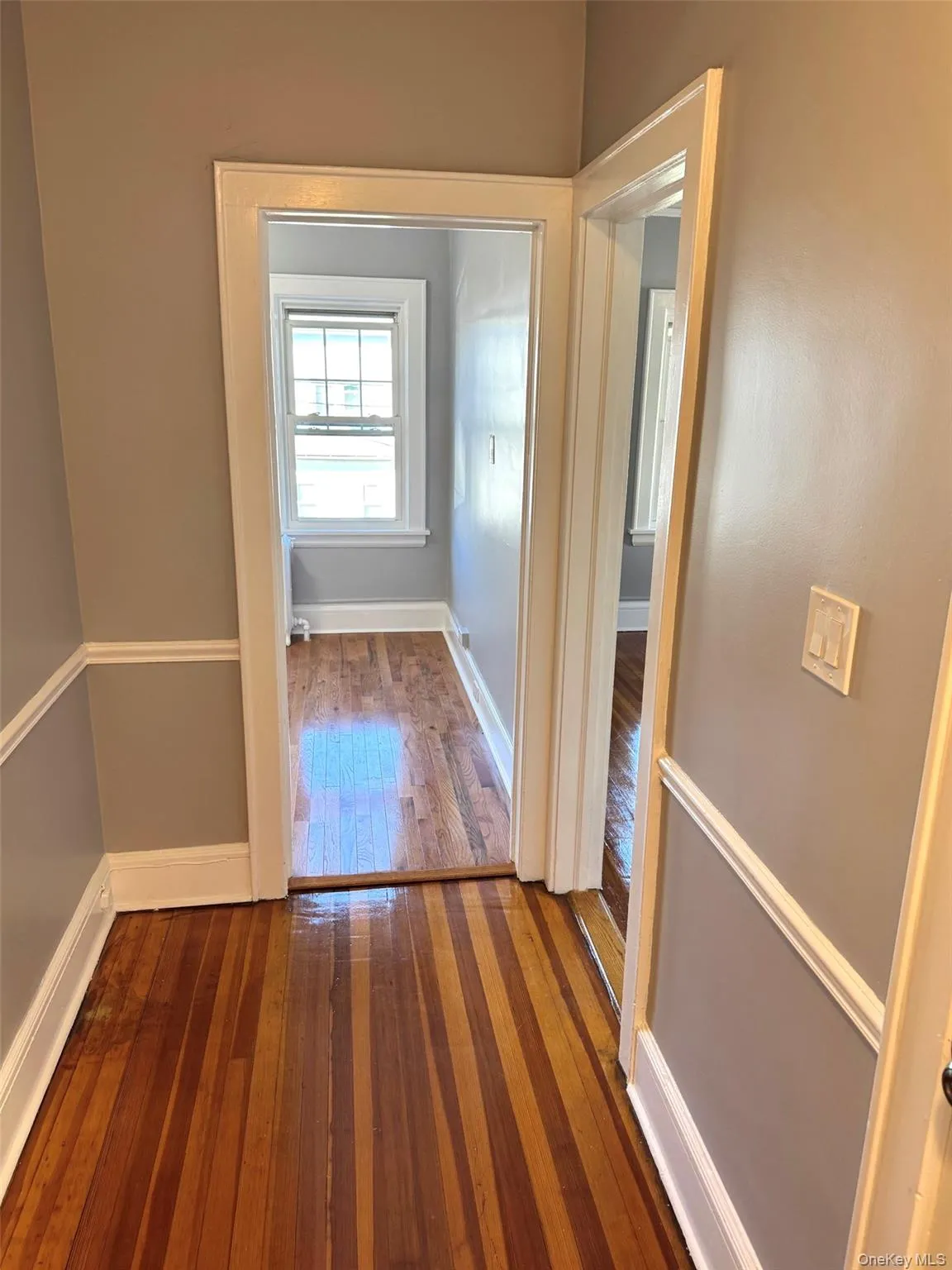 Hall with dark wood-type flooring and baseboards Hall with dark wood-type flooring and baseboards