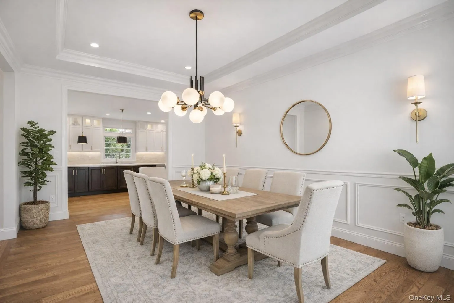 Dining space featuring light wood-style flooring, crown molding, a decorative wall, a chandelier, and a raised ceiling Dining space featuring light wood-style flooring, crown molding, a decorative wall, a chandelier, and a raised ceiling