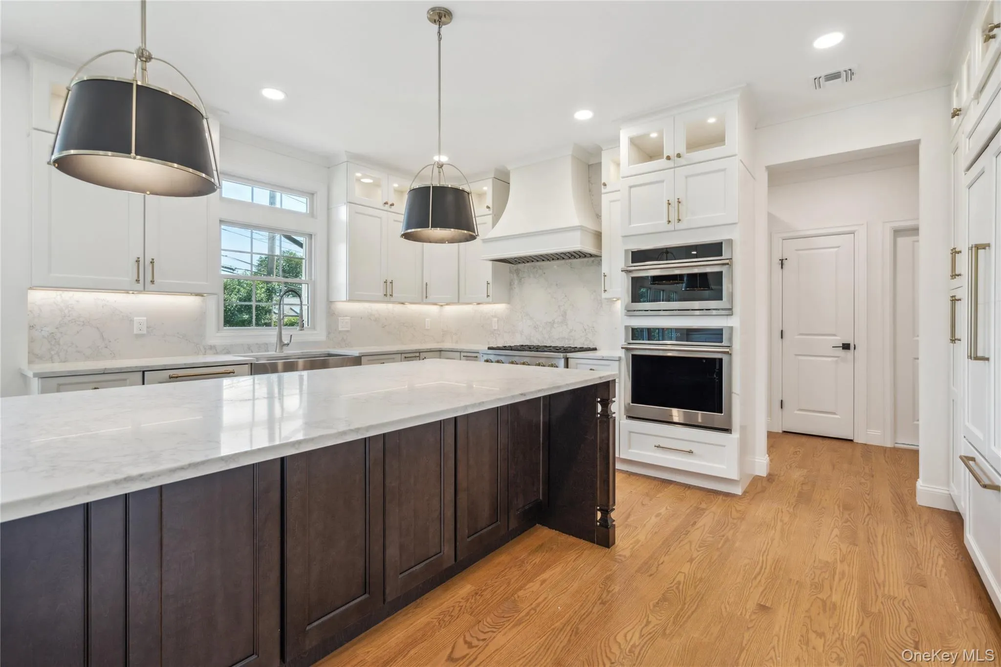 Kitchen featuring white cabinetry, tasteful backsplash, hanging light fixtures, glass insert cabinets, and recessed lighting Kitchen featuring white cabinetry, tasteful backsplash, hanging light fixtures, glass insert cabinets, and recessed lighting