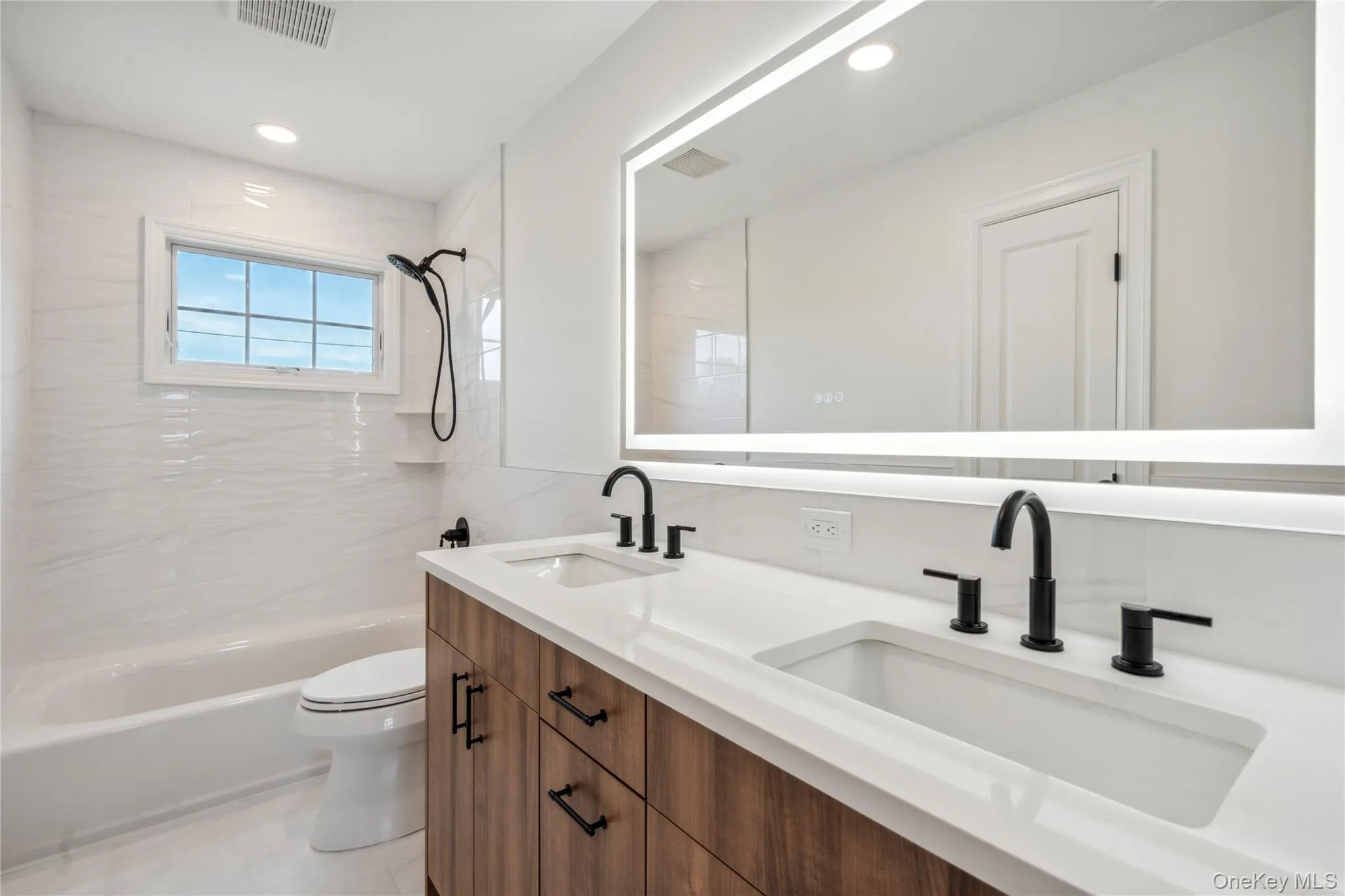 Bathroom featuring double vanity, shower / washtub combination, and recessed lighting Bathroom featuring double vanity, shower / washtub combination, and recessed lighting