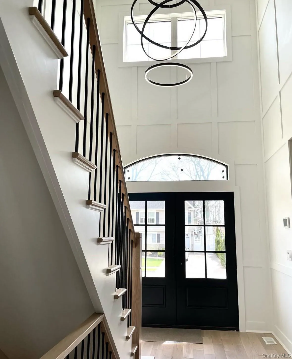 Entrance foyer featuring a decorative wall, light wood-style floors, french doors, and stairs Entrance foyer featuring a decorative wall, light wood-style floors, french doors, and stairs