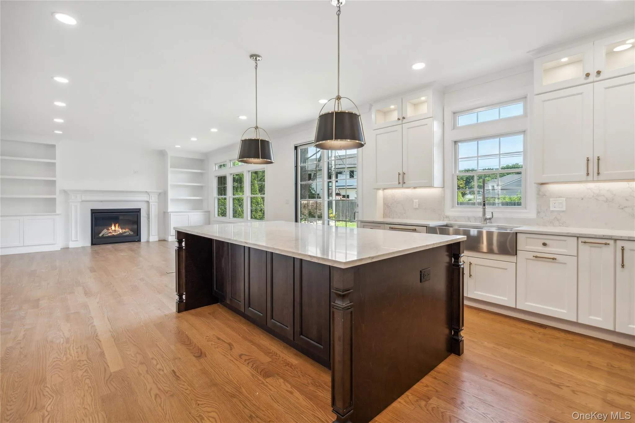 Kitchen featuring dark brown cabinets, white cabinetry, recessed lighting, a glass covered fireplace, and built in features Kitchen featuring dark brown cabinets, white cabinetry, recessed lighting, a glass covered fireplace, and built in features