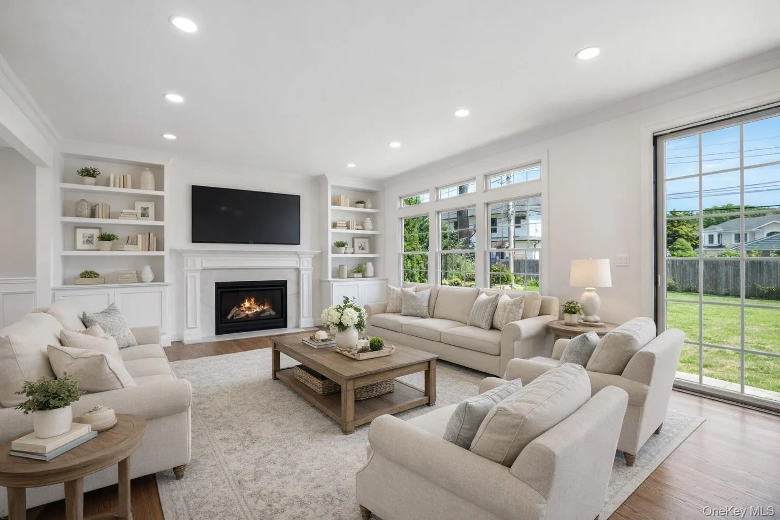 Living area with built in shelves, a fireplace with flush hearth, wood finished floors, ornamental molding, and recessed lighting Living area with built in shelves, a fireplace with flush hearth, wood finished floors, ornamental molding, and recessed lighting