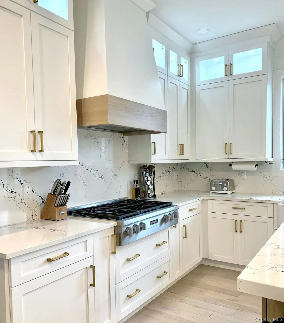 Kitchen with custom range hood, white cabinetry, and healthy amount of natural light Kitchen with custom range hood, white cabinetry, and healthy amount of natural light