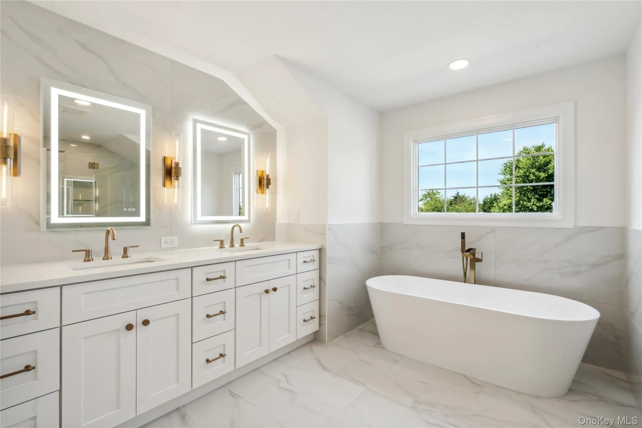 Full bathroom featuring tile walls, light marble finish floors, double vanity, recessed lighting, and wainscoting Full bathroom featuring tile walls, light marble finish floors, double vanity, recessed lighting, and wainscoting