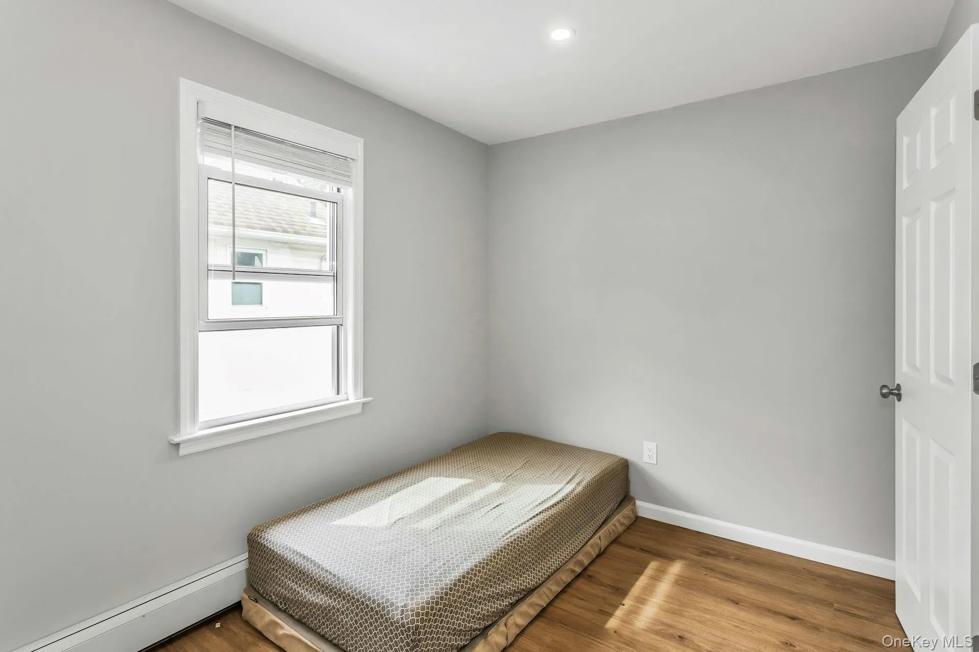 Bedroom with a baseboard heating unit, wood finished floors, and recessed lighting Bedroom with a baseboard heating unit, wood finished floors, and recessed lighting