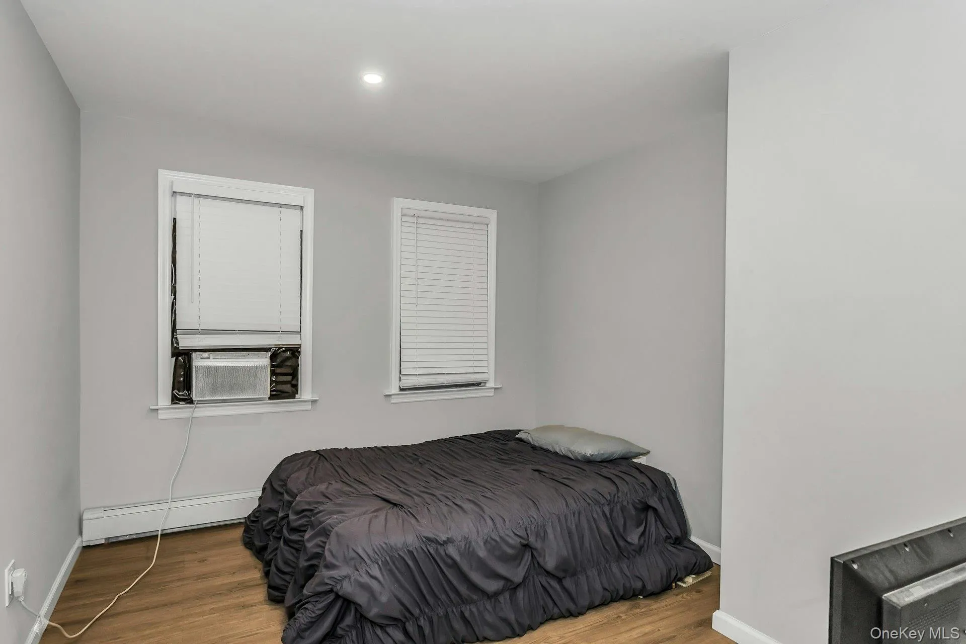 Bedroom with wood finished floors, a baseboard heating unit, recessed lighting, and cooling unit Bedroom with wood finished floors, a baseboard heating unit, recessed lighting, and cooling unit