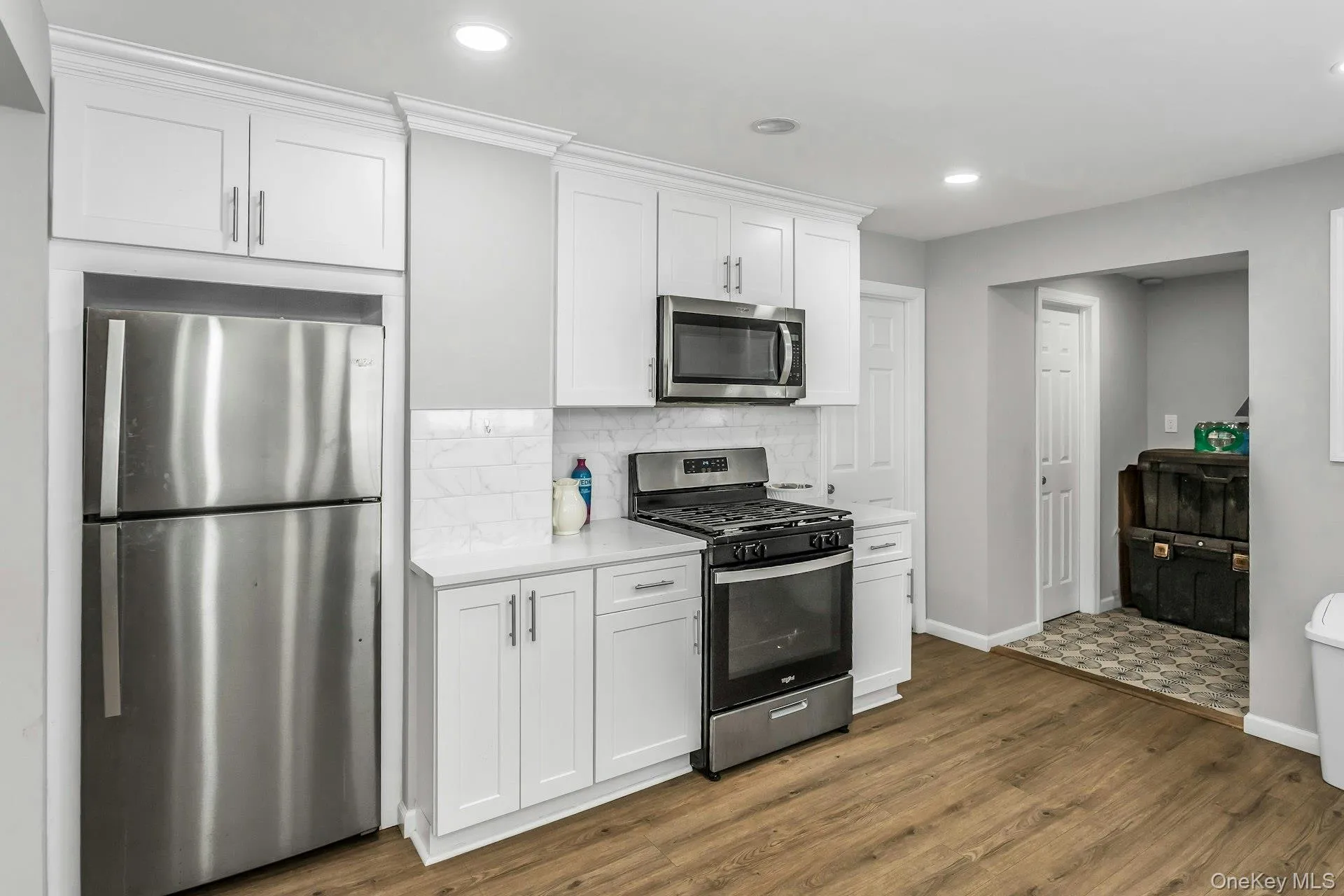 Kitchen featuring stainless steel appliances, white cabinets, decorative backsplash, dark wood finished floors, and recessed lighting Kitchen featuring stainless steel appliances, white cabinets, decorative backsplash, dark wood finished floors, and recessed lighting