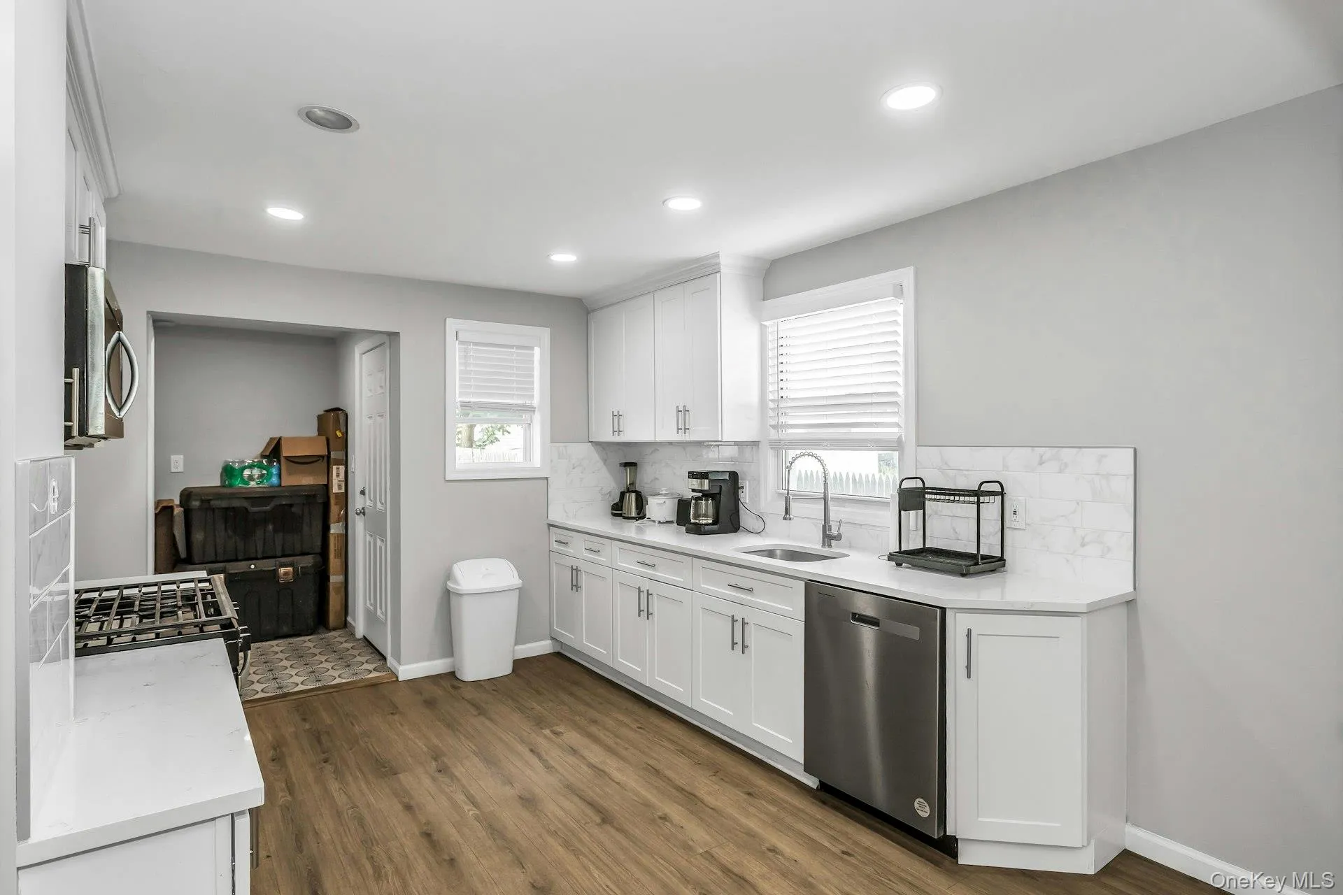 Kitchen featuring decorative backsplash, stainless steel appliances, white cabinetry, dark wood finished floors, and recessed lighting Kitchen featuring decorative backsplash, stainless steel appliances, white cabinetry, dark wood finished floors, and recessed lighting