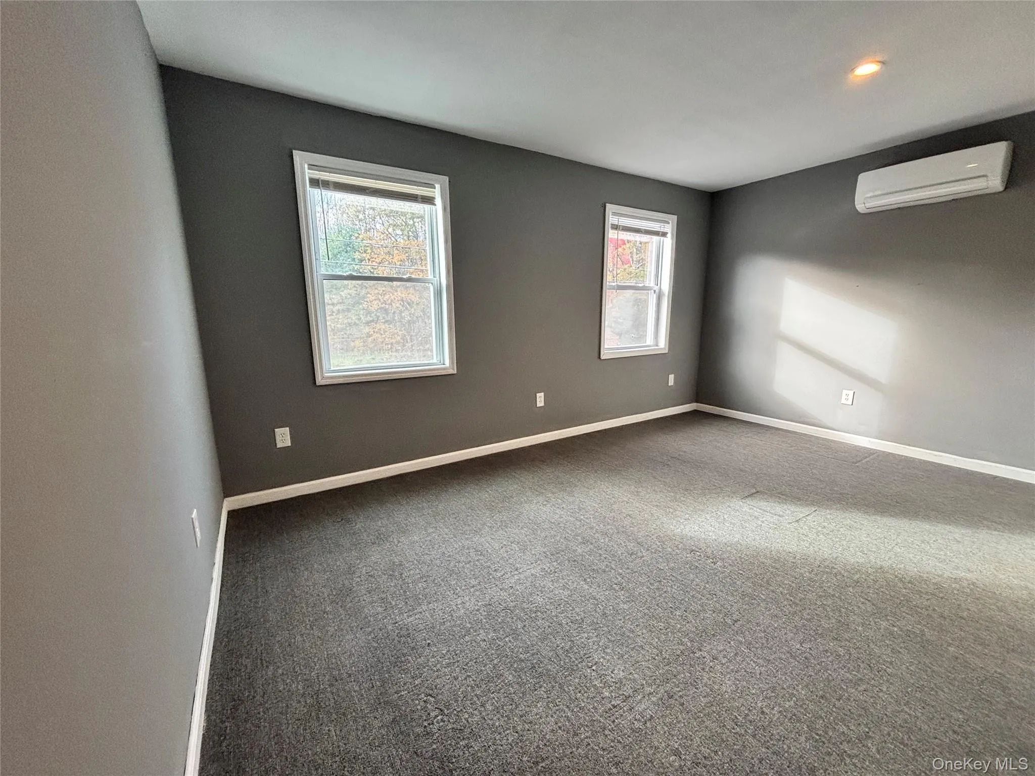 Empty room with carpet floors and a wall unit AC Empty room with carpet floors and a wall unit AC