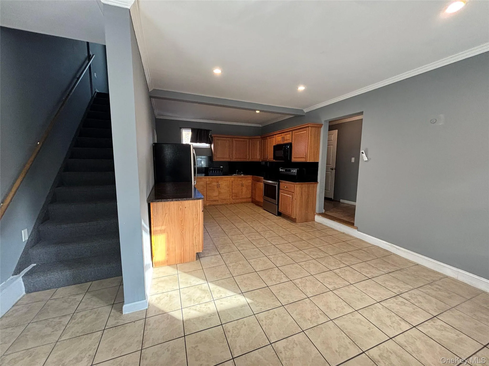 Kitchen with dark countertops, stainless steel appliances, crown molding, recessed lighting, and brown cabinetry Kitchen with dark countertops, stainless steel appliances, crown molding, recessed lighting, and brown cabinetry