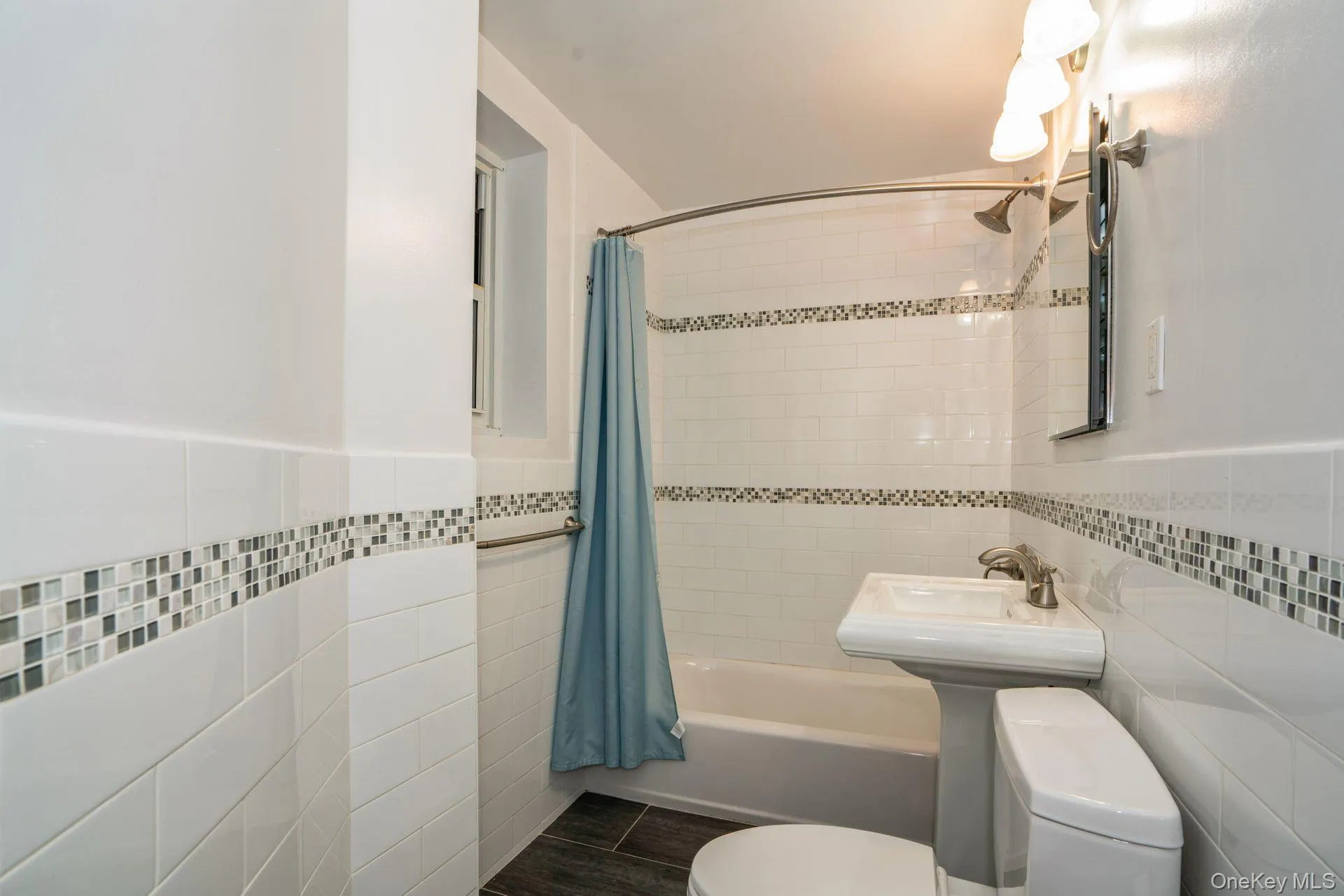 Full hall bath featuring tile walls, shower/bathtub combo Full hall bath featuring tile walls, shower/bathtub combo