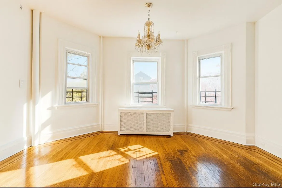 Unfurnished dining area with radiator heating unit, wood-type flooring, and a chandelier Unfurnished dining area with radiator heating unit, wood-type flooring, and a chandelier