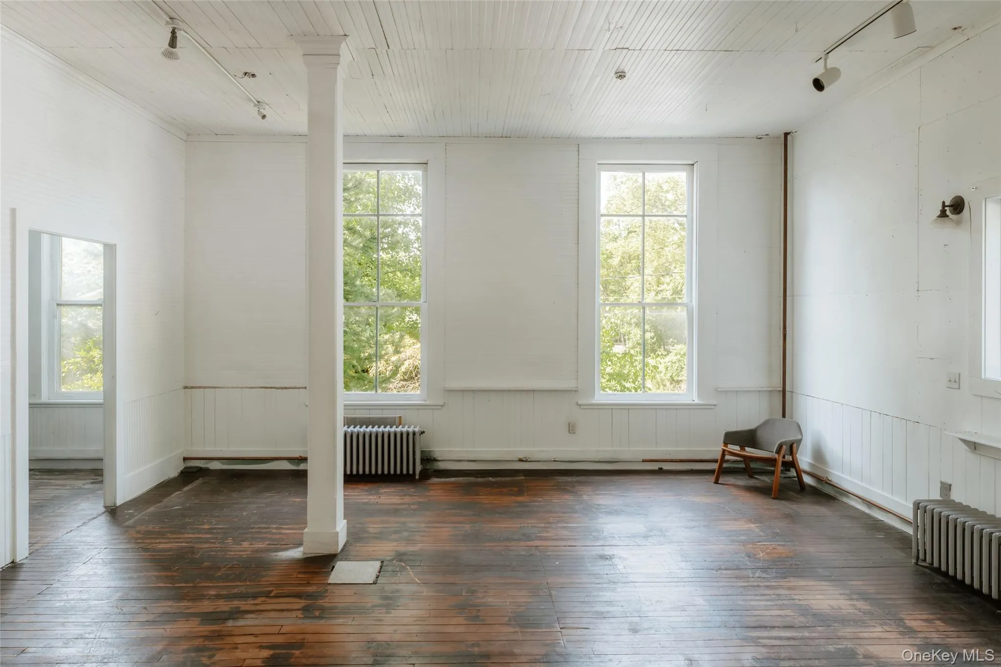 Unfurnished room featuring track lighting, dark wood-type flooring, and healthy amount of natural light Unfurnished room featuring track lighting, dark wood-type flooring, and healthy amount of natural light