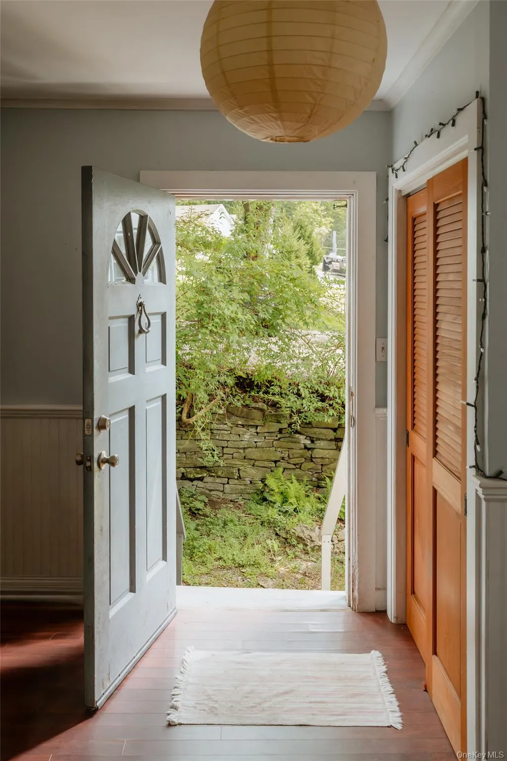 Doorway with wood finished floors, crown molding, and a wainscoted wall Doorway with wood finished floors, crown molding, and a wainscoted wall