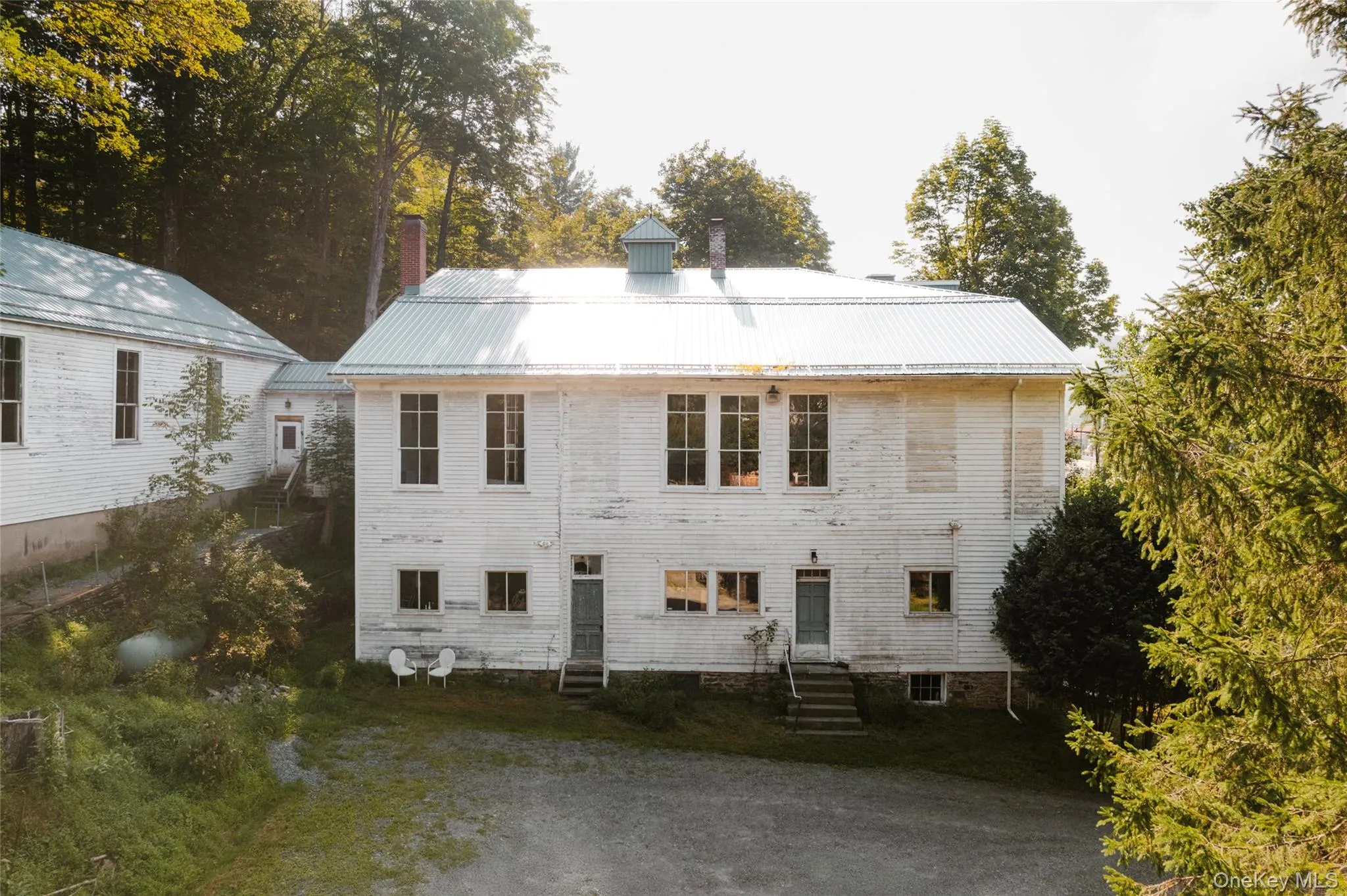 Rear view of house featuring entry steps, a metal roof, and a chimney Rear view of house featuring entry steps, a metal roof, and a chimney