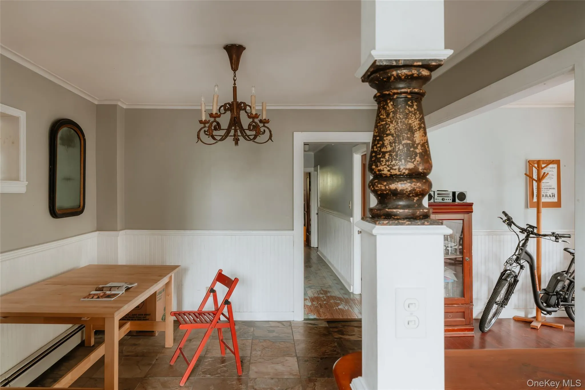 Dining room with ornamental molding, a baseboard radiator, a chandelier, wainscoting, and stone finish floors Dining room with ornamental molding, a baseboard radiator, a chandelier, wainscoting, and stone finish floors