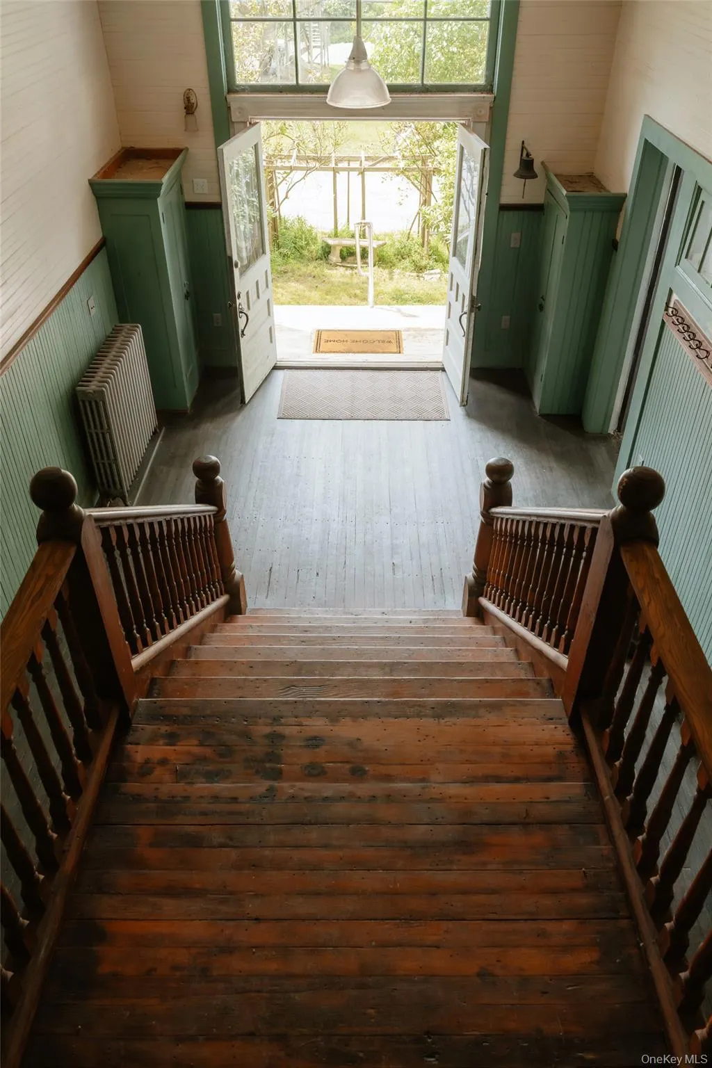 Stairs featuring hardwood / wood-style floors, wooden walls, radiator heating unit, and wainscoting Stairs featuring hardwood / wood-style floors, wooden walls, radiator heating unit, and wainscoting