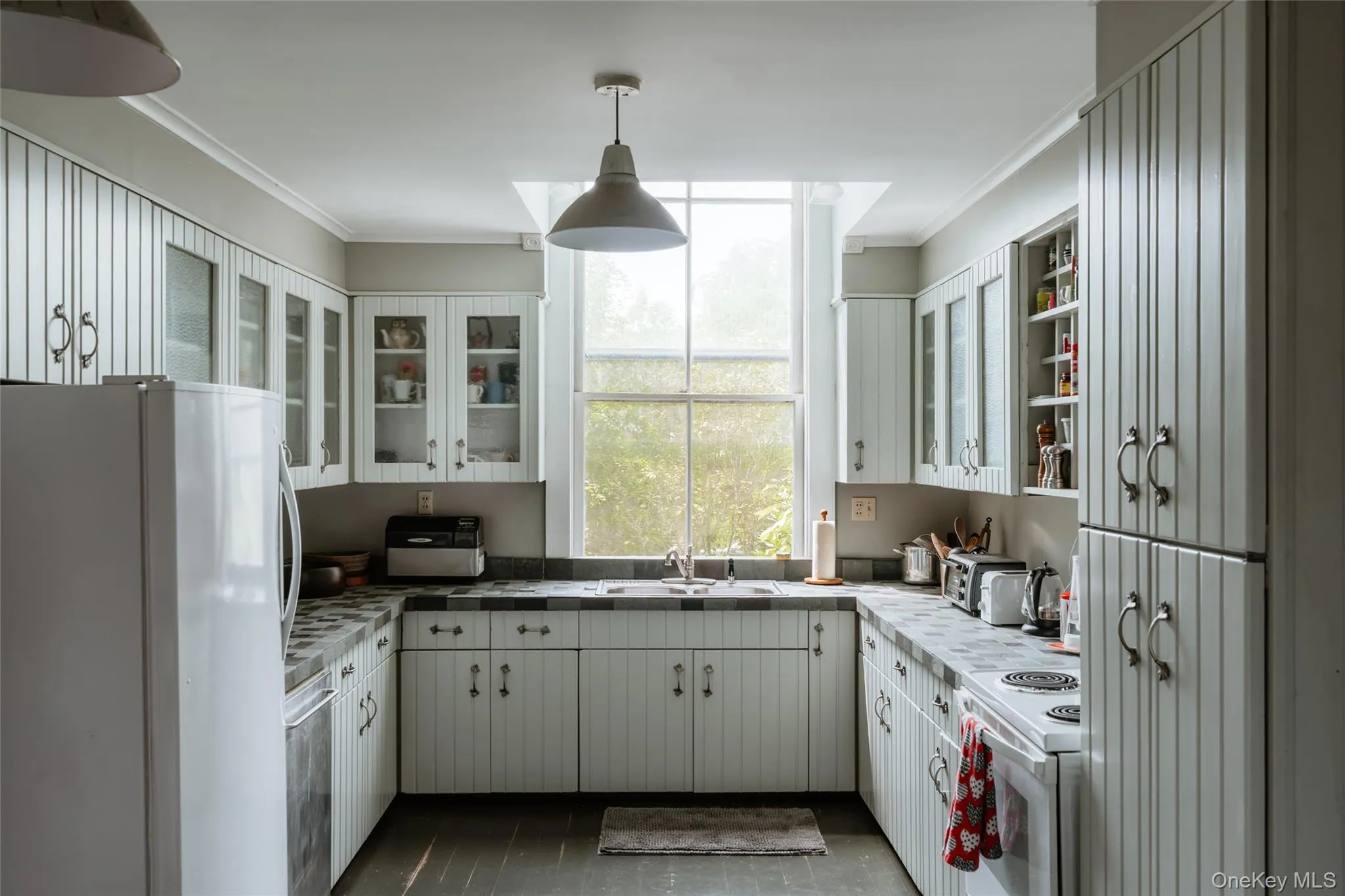 Kitchen with white appliances, white cabinets, crown molding, pendant lighting, and glass insert cabinets Kitchen with white appliances, white cabinets, crown molding, pendant lighting, and glass insert cabinets