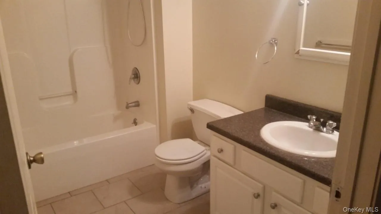 Bathroom featuring vanity, tub / shower combination, and light tile patterned flooring Bathroom featuring vanity, tub / shower combination, and light tile patterned flooring