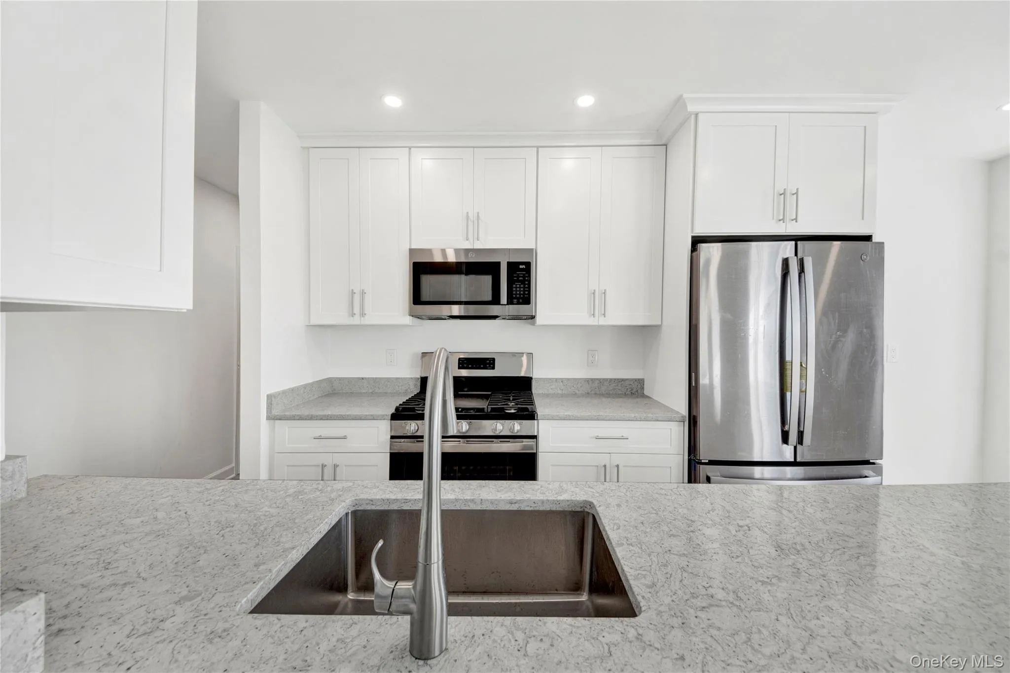 Kitchen featuring stainless steel appliances, white cabinetry, recessed lighting, and light stone countertops Kitchen featuring stainless steel appliances, white cabinetry, recessed lighting, and light stone countertops