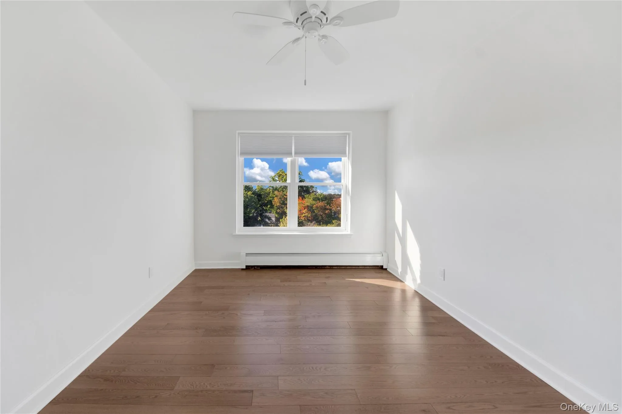Unfurnished room with hardwood / wood-style floors, a baseboard radiator, and ceiling fan Unfurnished room with hardwood / wood-style floors, a baseboard radiator, and ceiling fan