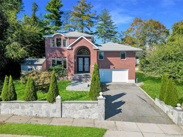 View of front of home with brick siding, asphalt driveway, a garage, and a shingled roof