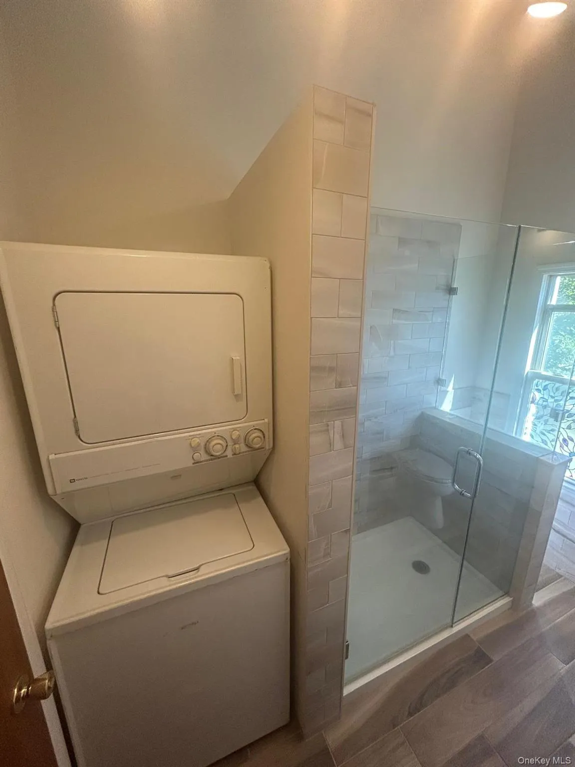 Full bath featuring a stall shower and stacked washing machine and dryer Full bath featuring a stall shower and stacked washing machine and dryer