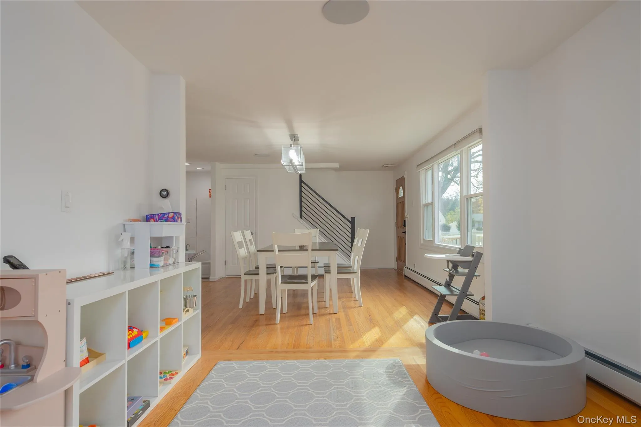 Dining room featuring light wood-style flooring, a baseboard heating unit, stairway, and baseboard heating Dining room featuring light wood-style flooring, a baseboard heating unit, stairway, and baseboard heating
