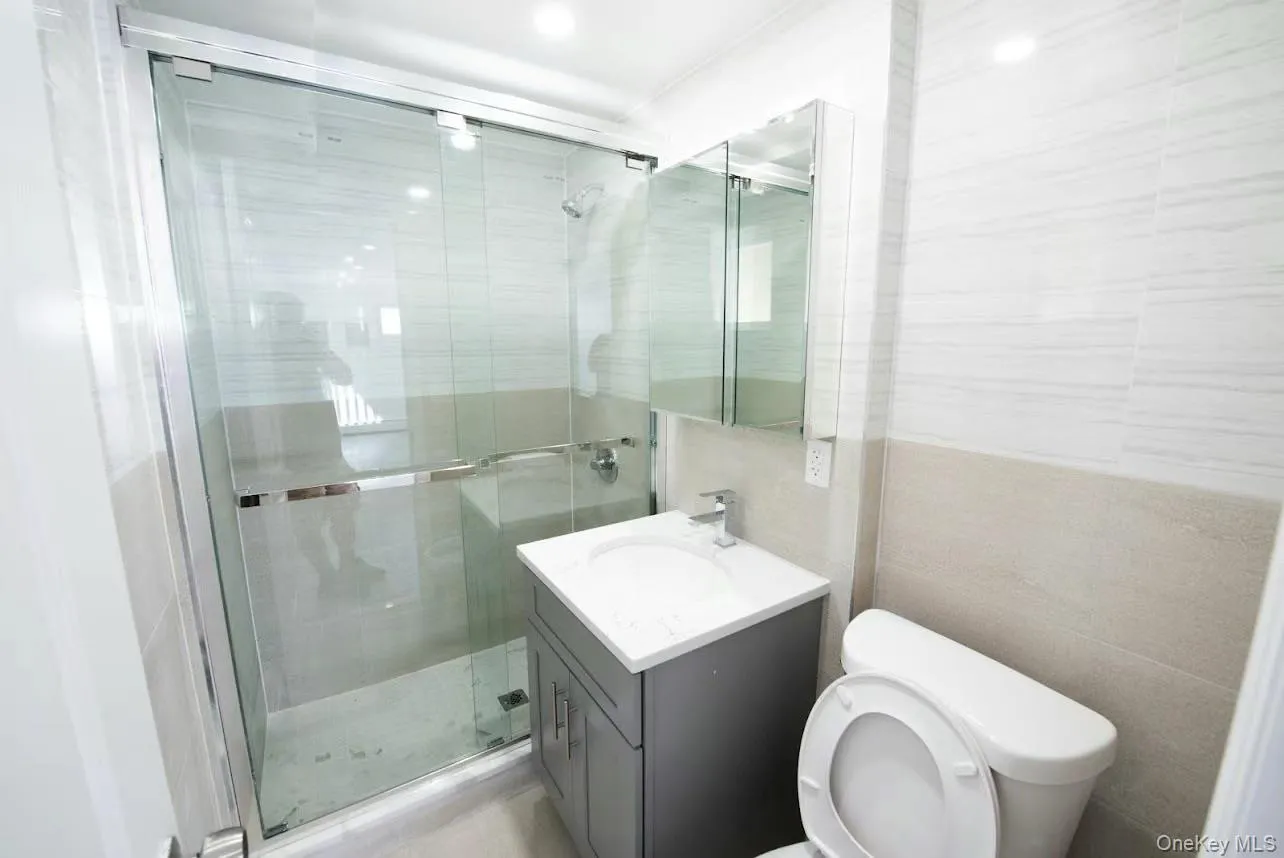 Bathroom featuring vanity, a stall shower, and tile walls Bathroom featuring vanity, a stall shower, and tile walls