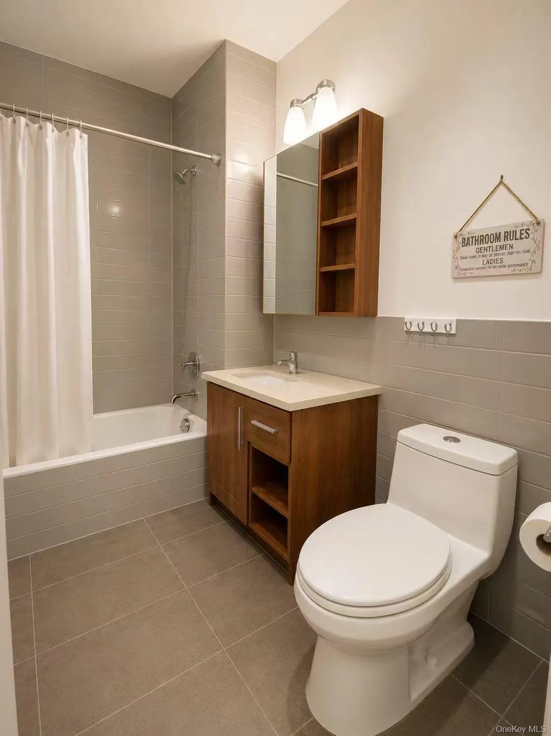 Full bath with tile walls, tiled shower / bath combo, vanity, and dark tile patterned flooring Full bath with tile walls, tiled shower / bath combo, vanity, and dark tile patterned flooring
