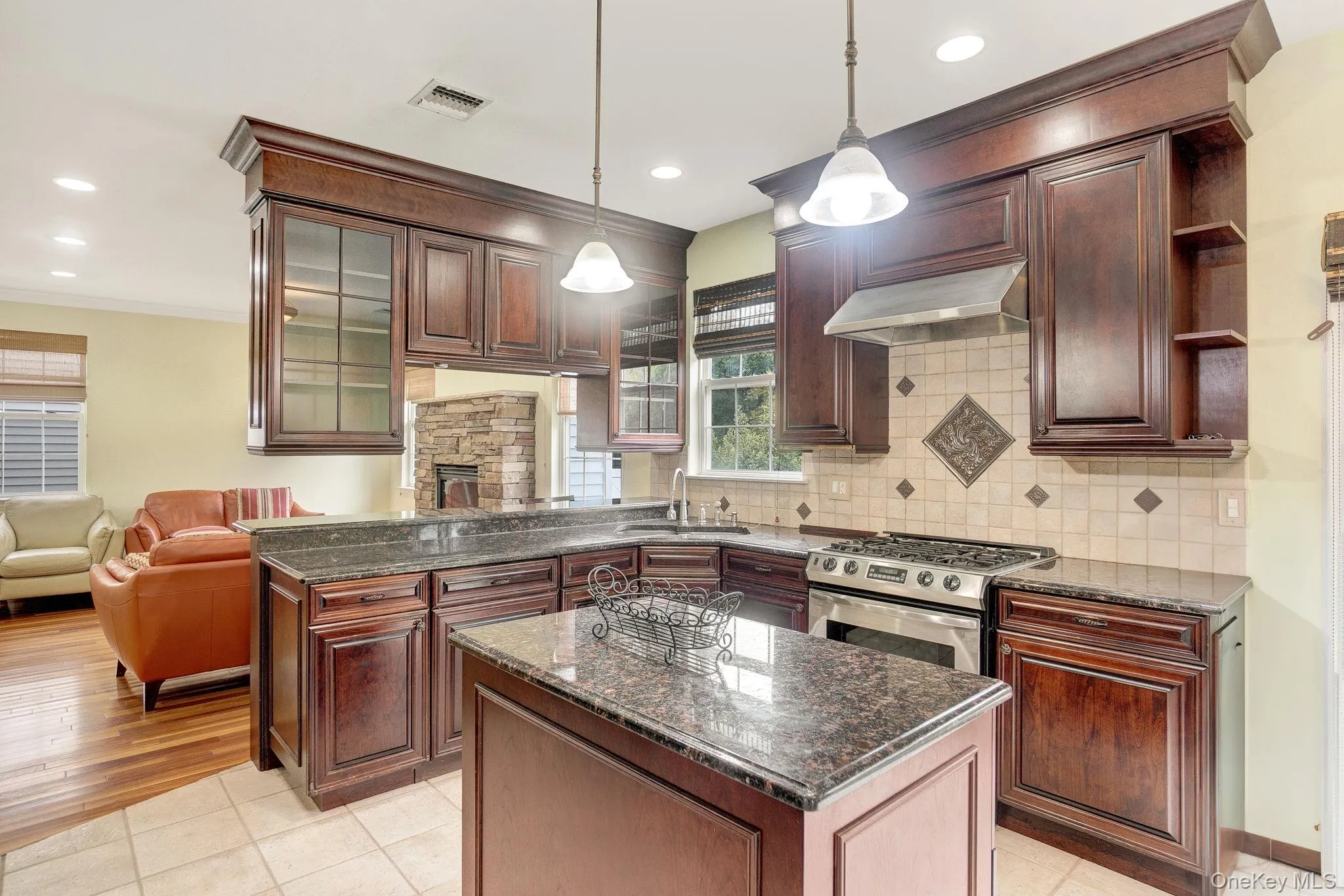 Kitchen with dark stone counters, hanging light fixtures, gas stove, light tile patterned floors, and open shelves Kitchen with dark stone counters, hanging light fixtures, gas stove, light tile patterned floors, and open shelves
