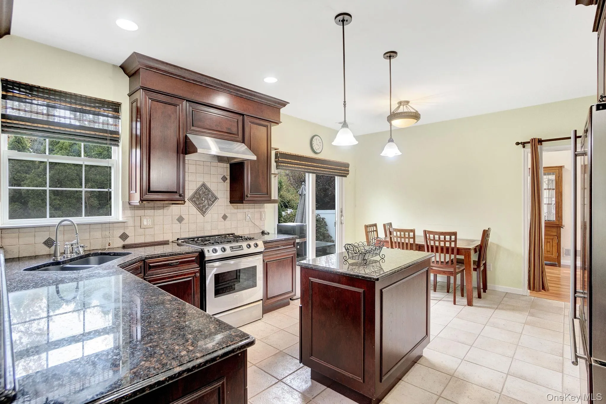 Kitchen with a center island, stainless steel appliances, backsplash, decorative light fixtures, and dark brown cabinets Kitchen with a center island, stainless steel appliances, backsplash, decorative light fixtures, and dark brown cabinets