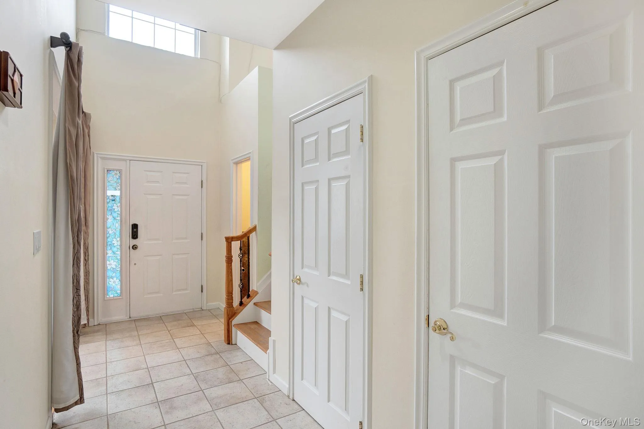 Foyer entrance featuring light tile patterned floors, stairs, and a towering ceiling Foyer entrance featuring light tile patterned floors, stairs, and a towering ceiling
