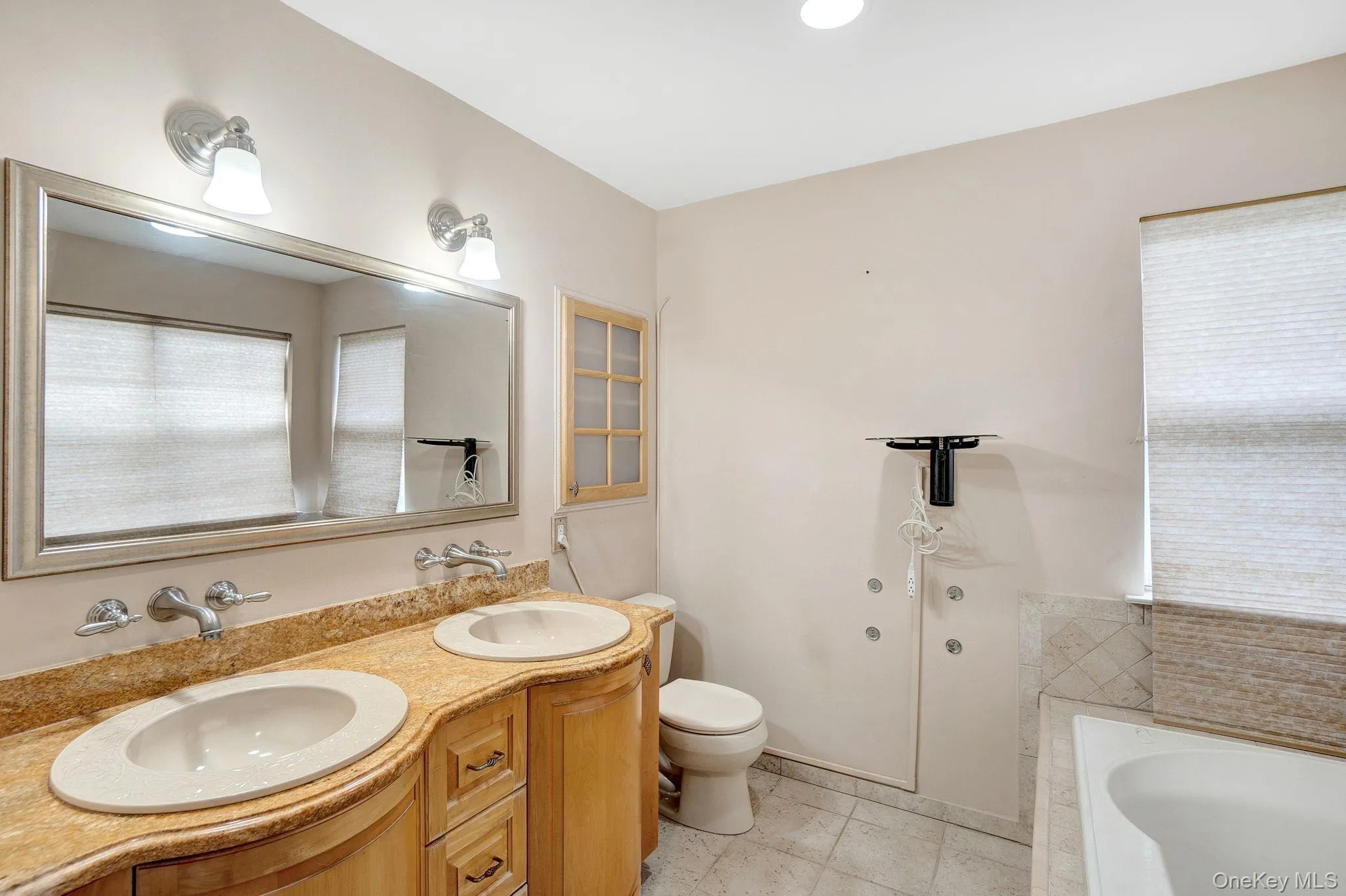 Bathroom with double vanity, tiled tub, and light tile patterned floors Bathroom with double vanity, tiled tub, and light tile patterned floors