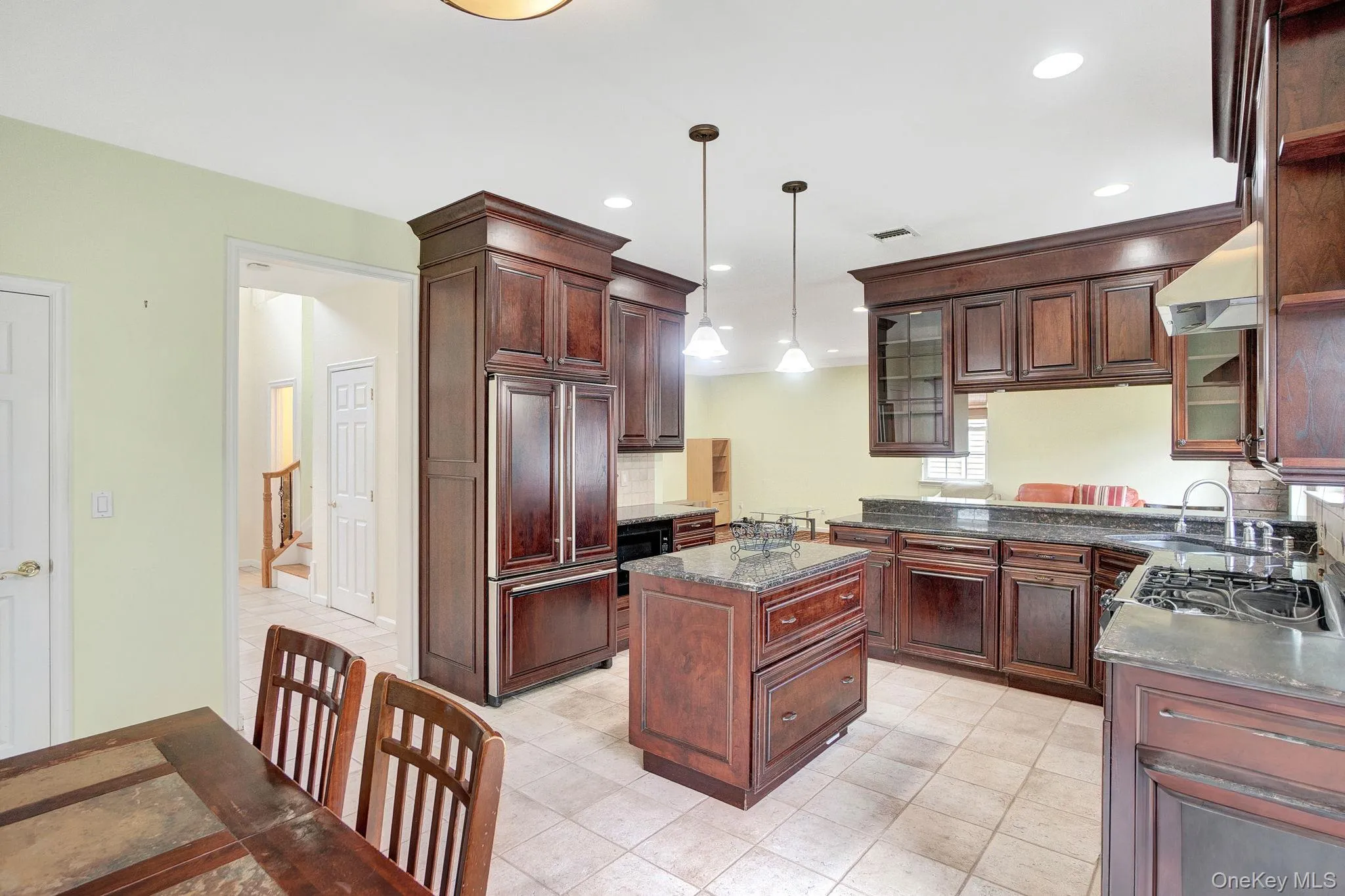 Kitchen featuring a center island, glass insert cabinets, pendant lighting, paneled refrigerator, and dark stone counters Kitchen featuring a center island, glass insert cabinets, pendant lighting, paneled refrigerator, and dark stone counters