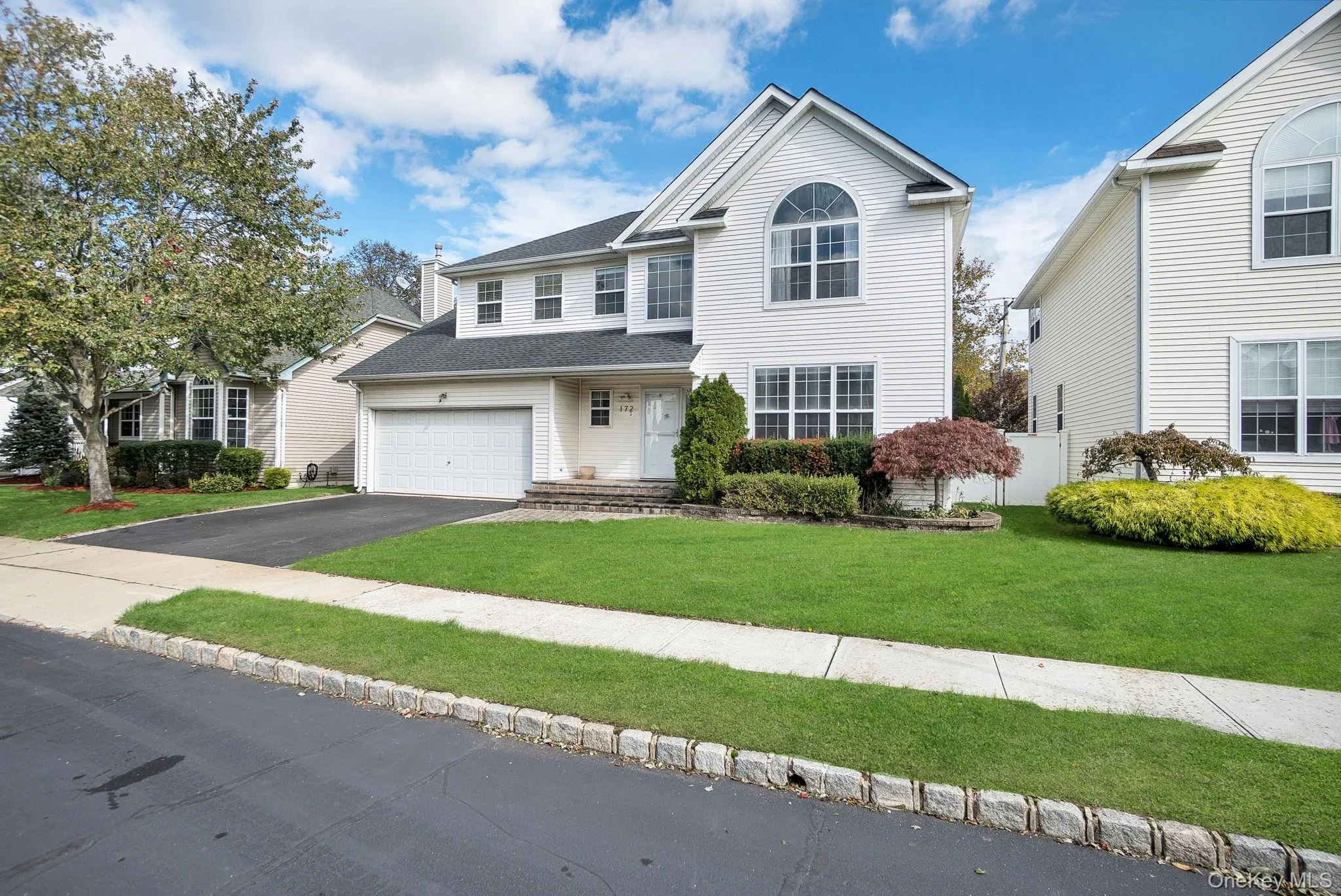Traditional home featuring a front yard, driveway, and a garage Traditional home featuring a front yard, driveway, and a garage