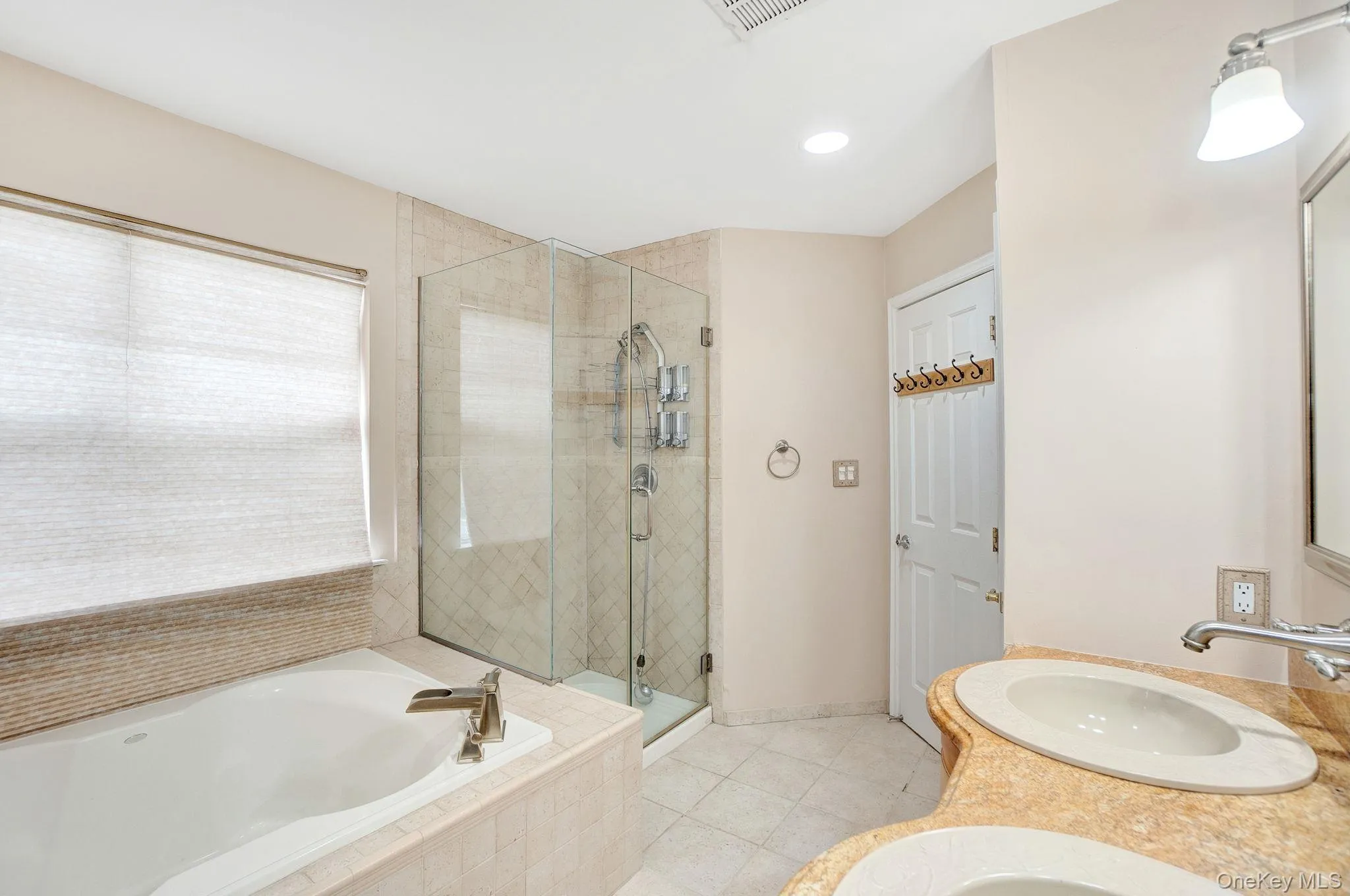 Full bath with light tile patterned flooring, double vanity, a garden tub, a shower stall, and recessed lighting Full bath with light tile patterned flooring, double vanity, a garden tub, a shower stall, and recessed lighting
