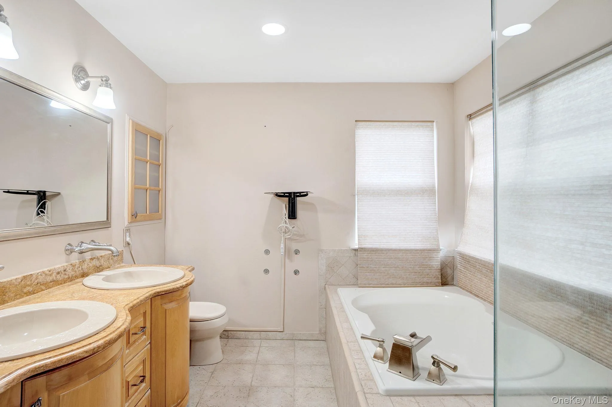 Full bathroom featuring a bath, double vanity, recessed lighting, and light tile patterned floors Full bathroom featuring a bath, double vanity, recessed lighting, and light tile patterned floors
