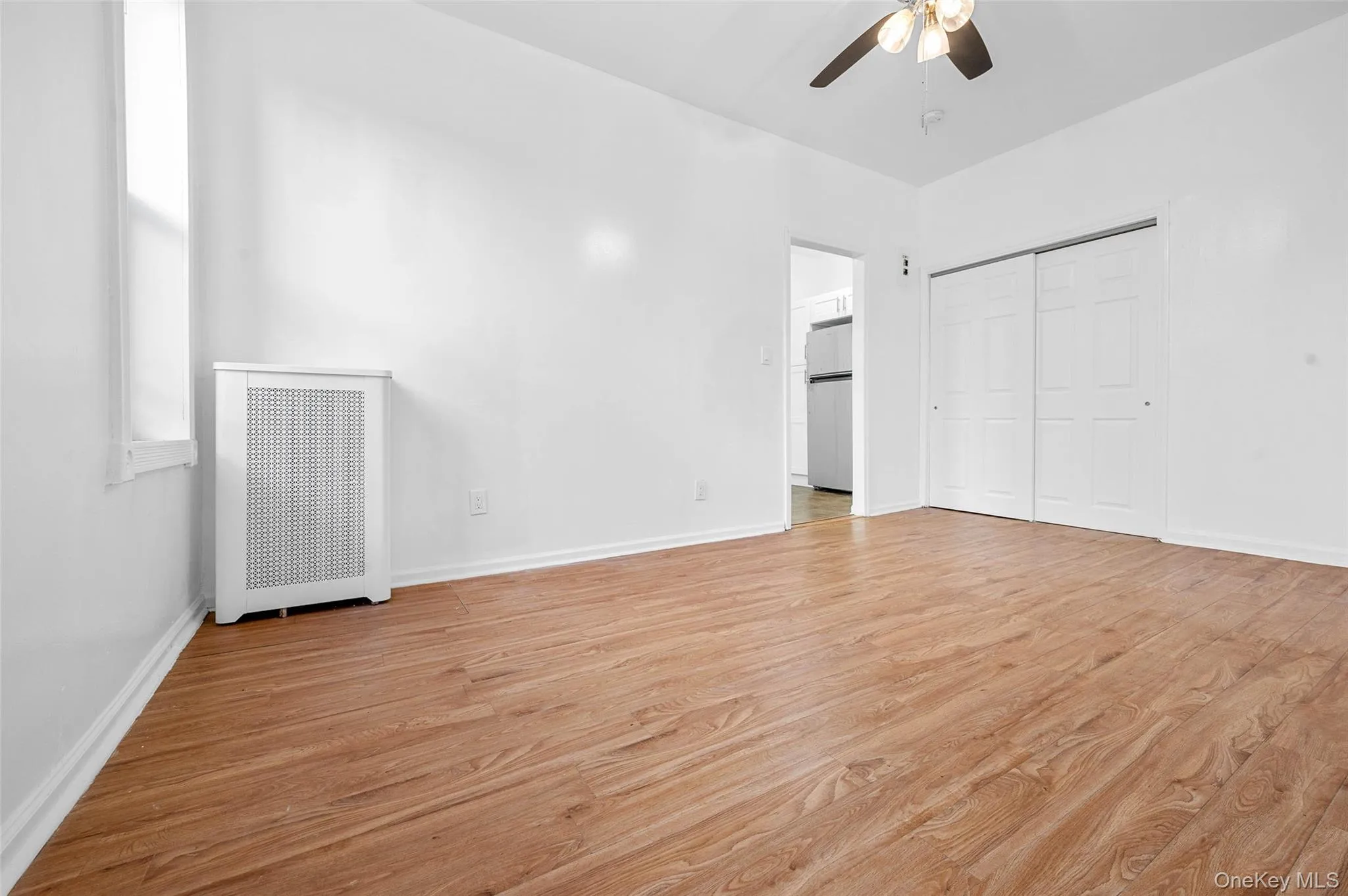 Unfurnished bedroom with radiator, light wood-type flooring, a closet, and ceiling fan Unfurnished bedroom with radiator, light wood-type flooring, a closet, and ceiling fan