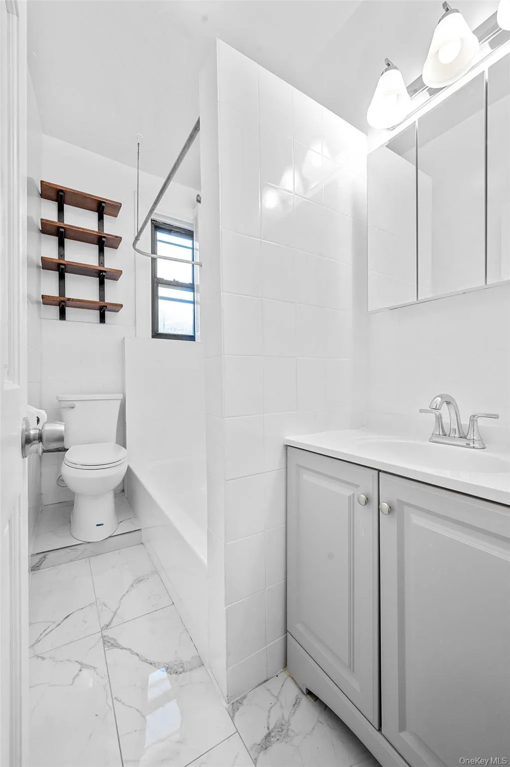 Bathroom with tile walls, vanity, light marble finish flooring, and shower / washtub combination Bathroom with tile walls, vanity, light marble finish flooring, and shower / washtub combination
