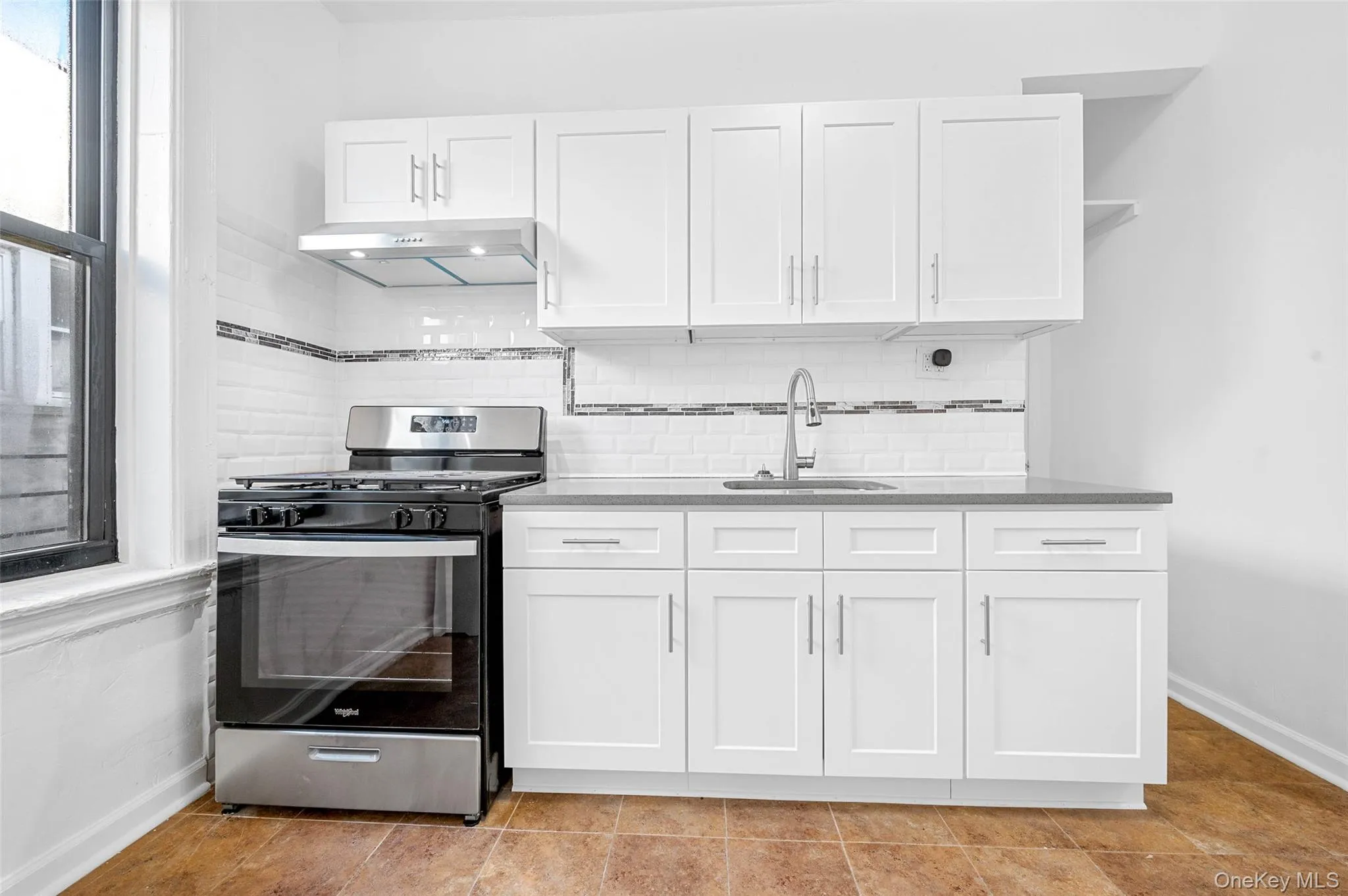 Kitchen featuring stainless steel gas range, white cabinetry, extractor fan, open shelves, and tasteful backsplash Kitchen featuring stainless steel gas range, white cabinetry, extractor fan, open shelves, and tasteful backsplash